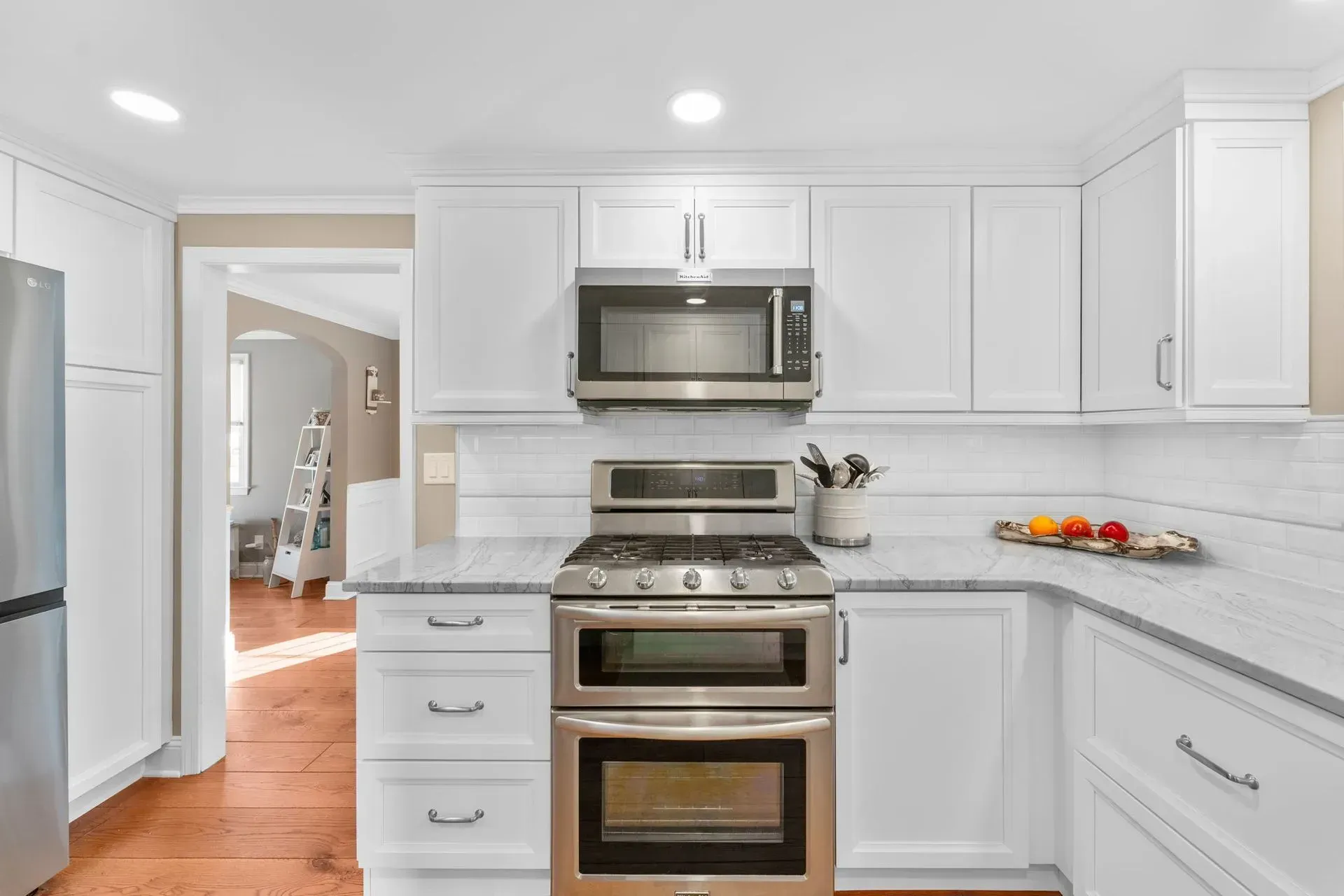 Bright white kitchen with stainless steel appliances, white cabinets, and hardwood floors  In Bucks County PA