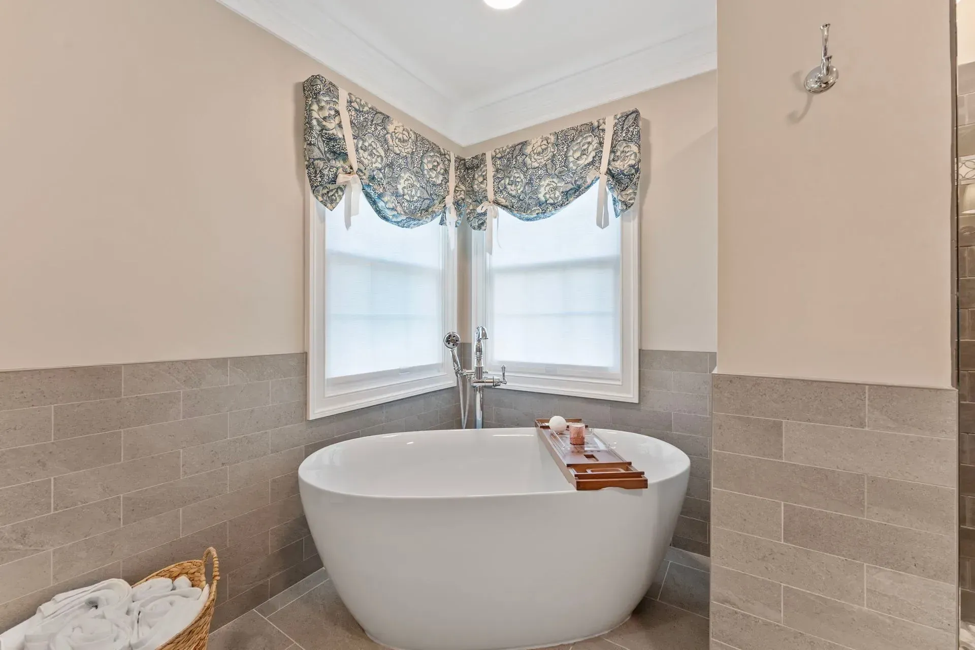 Bathroom with a freestanding white tub beneath two windows and blue patterned valances In Bucks County PA