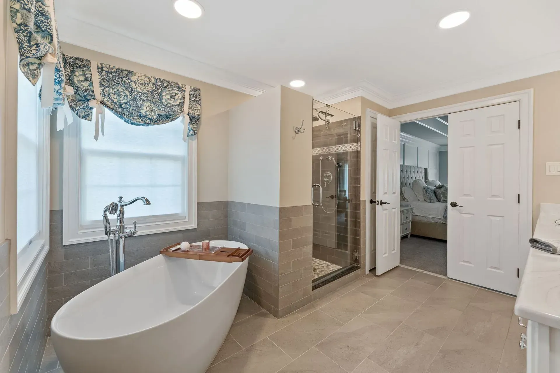 Bright modern bathroom with freestanding tub, glass shower, window, and white vanity In Bucks County PA