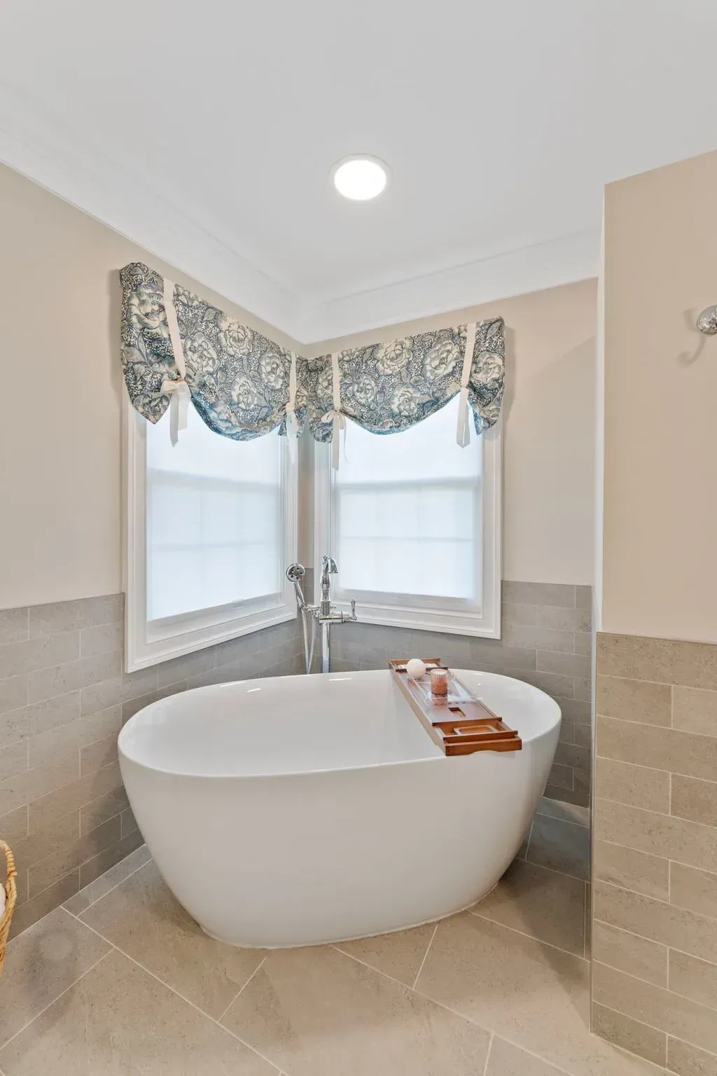 Bright bathroom corner with freestanding tub, two windows, and decorative valance In Bucks County PA