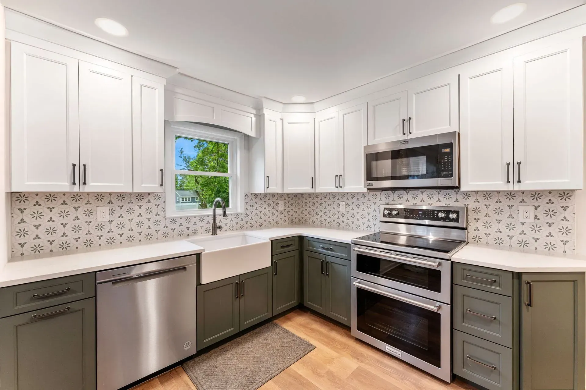Bright modern kitchen with white cabinets, stainless appliances, patterned backsplash, and a window above the sink  In Bucks County PA