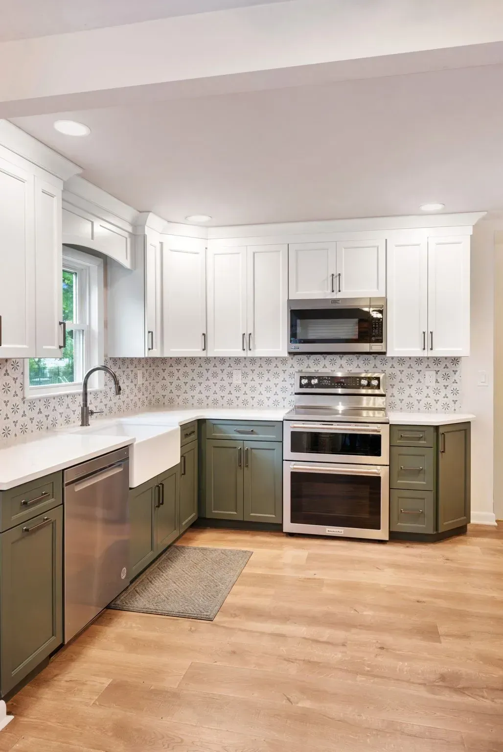 Bright modern kitchen with white cabinets, stainless appliances, gray tile backsplash, and wood floors  In Bucks County PA
