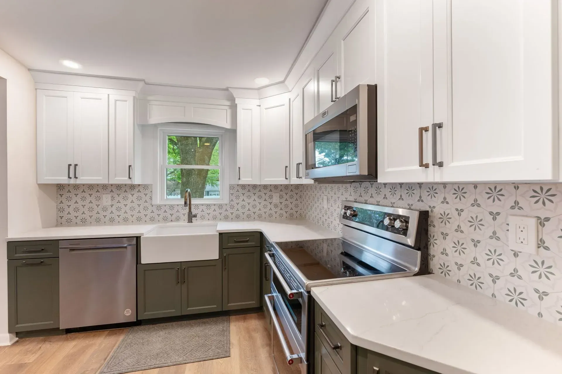 Modern white kitchen with dark lower cabinets, stainless appliances, and a window over the sink  In Bucks County PA