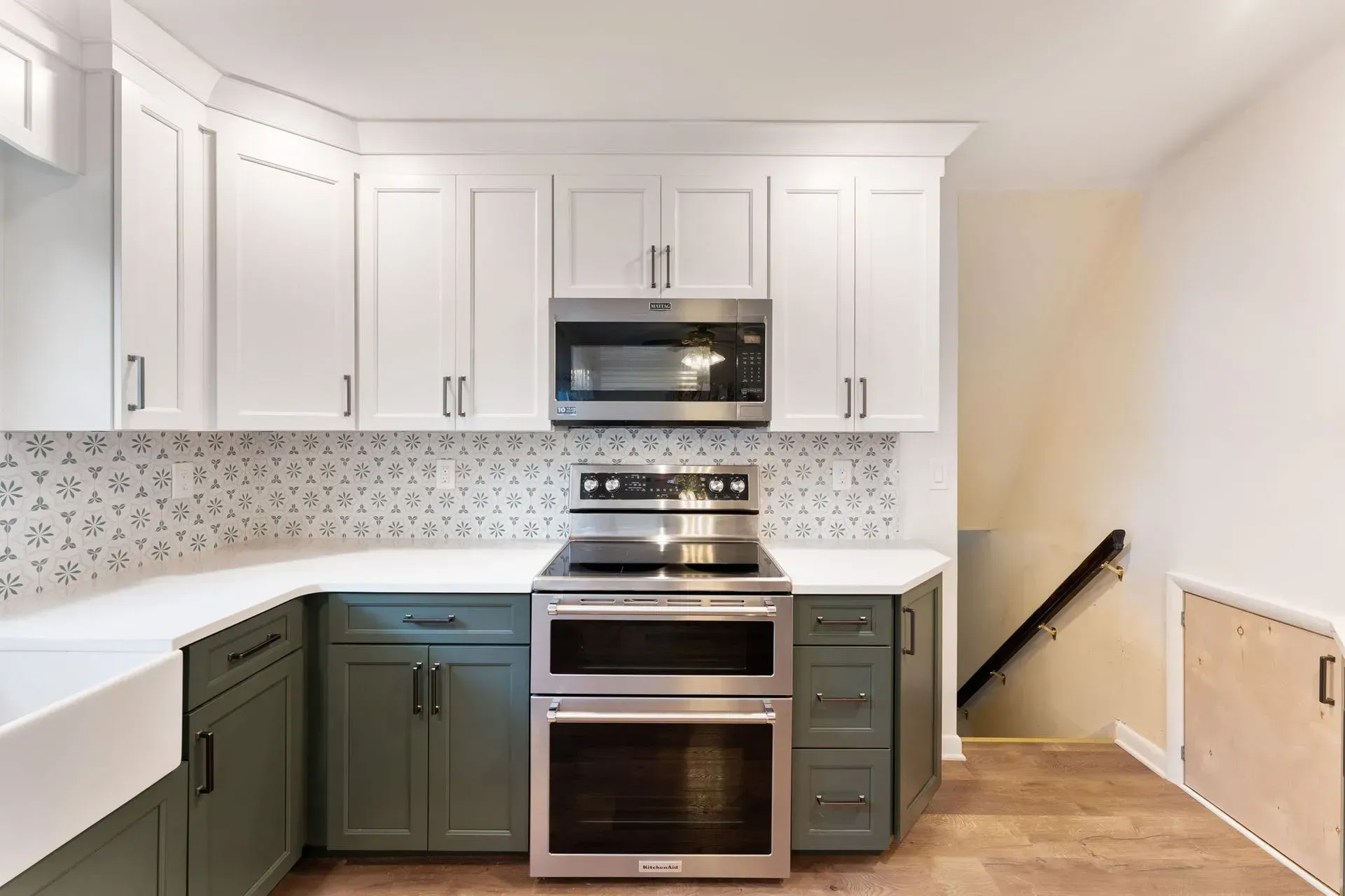 Modern kitchen with white cabinets, green lower cabinets, stainless steel appliances, and tiled backsplash  In Bucks County PA