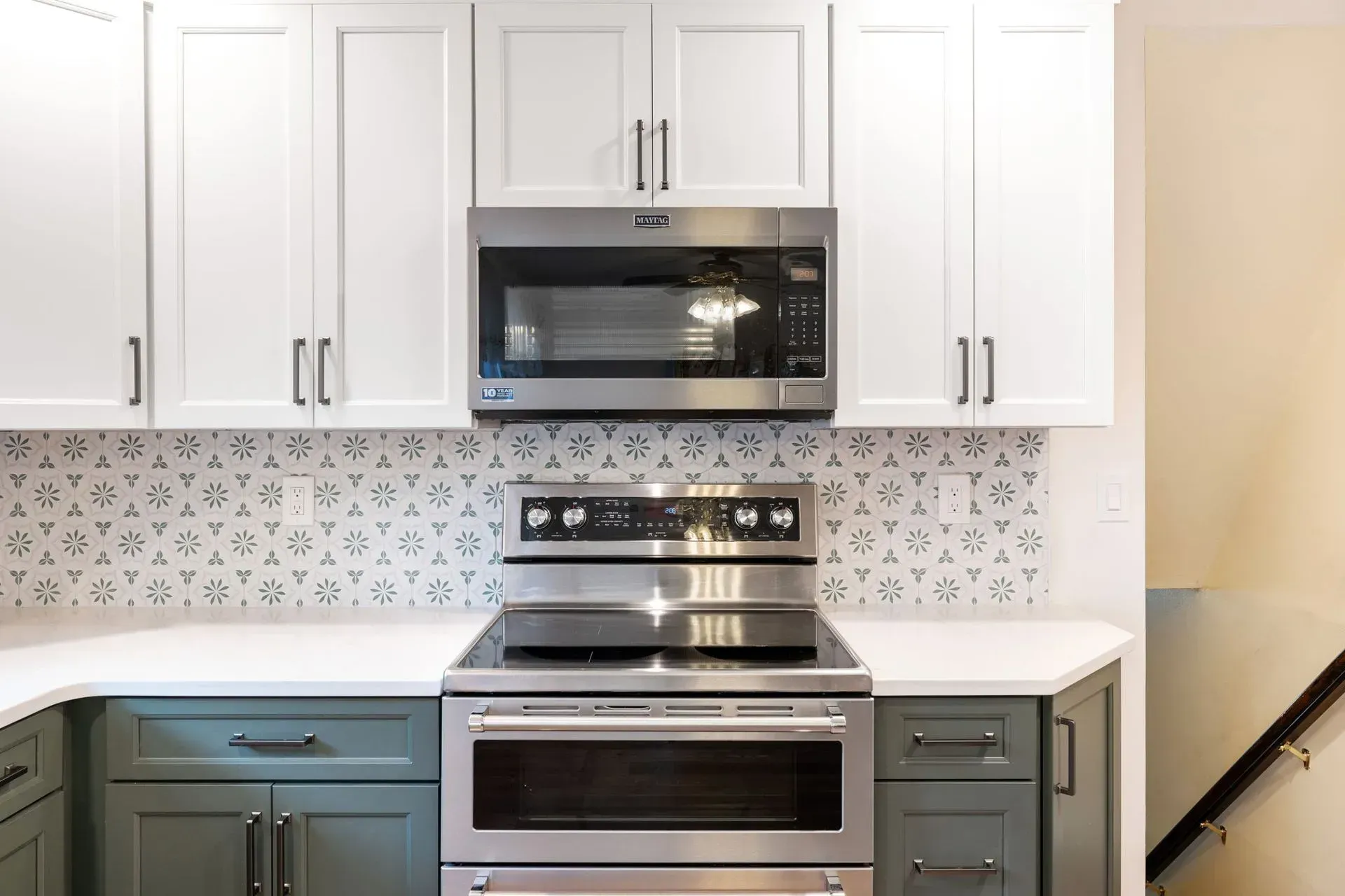 Modern kitchen with white cabinets, stainless steel oven and microwave, patterned backsplash, and teal lower cabinets  In Bucks County PA