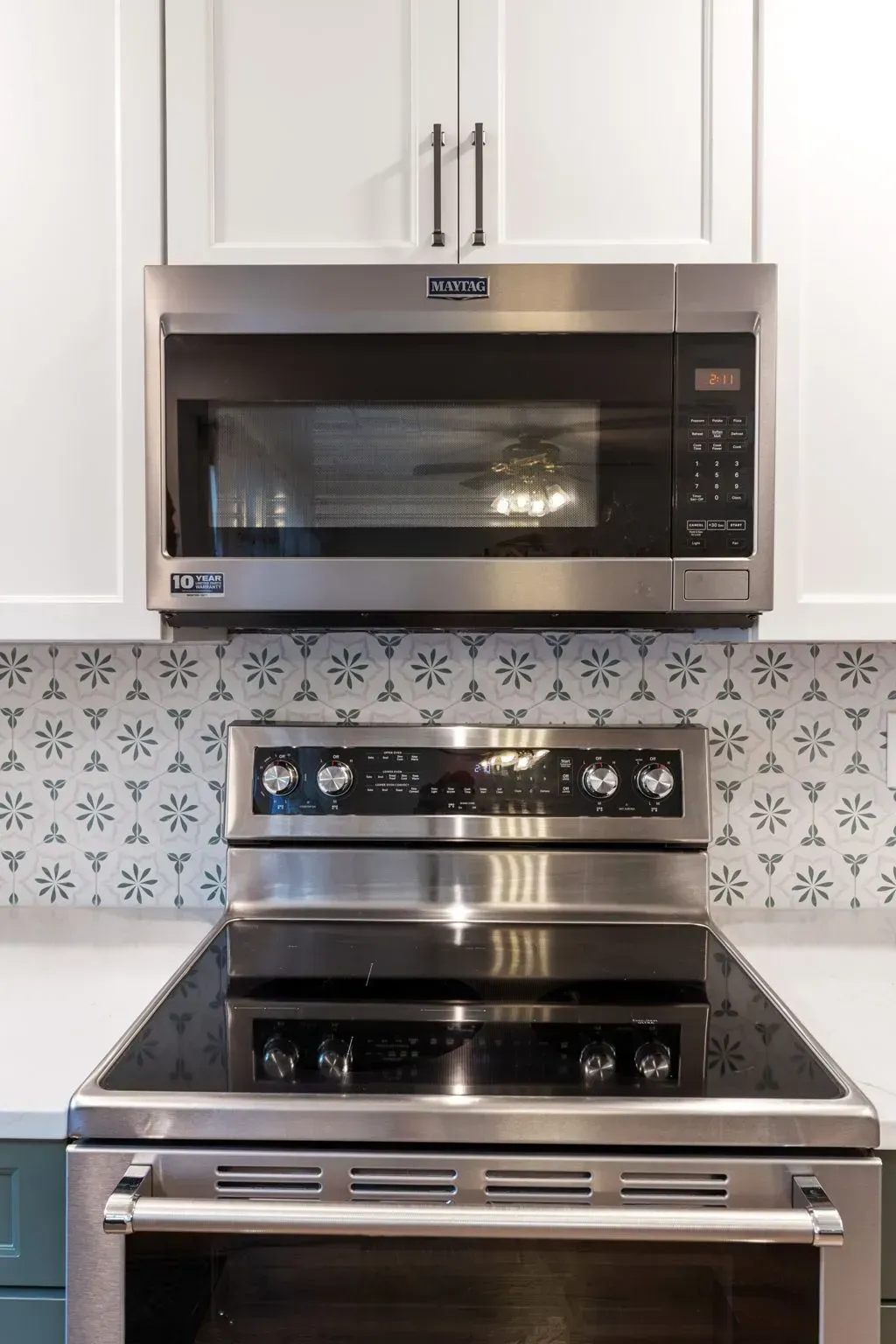 Stainless steel microwave above a matching electric range in a white kitchen with patterned tile backsplash  In Bucks County PA