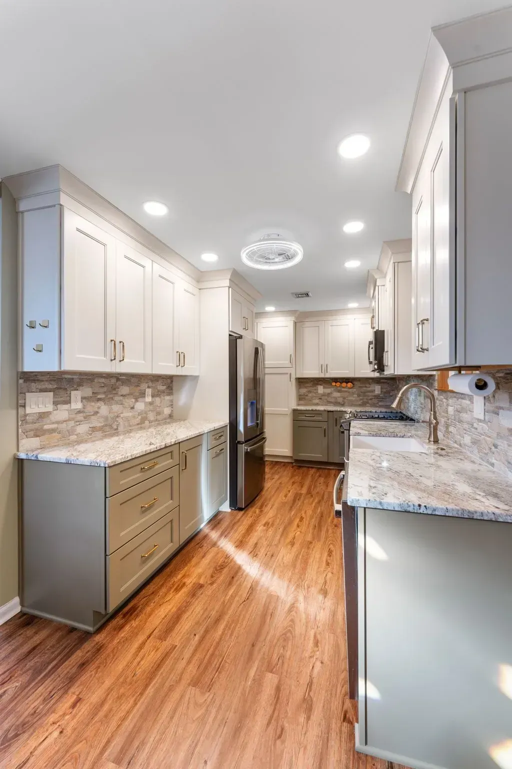 Bright modern kitchen with white cabinets, stainless appliances, granite counters, and hardwood floors In Bucks County PA