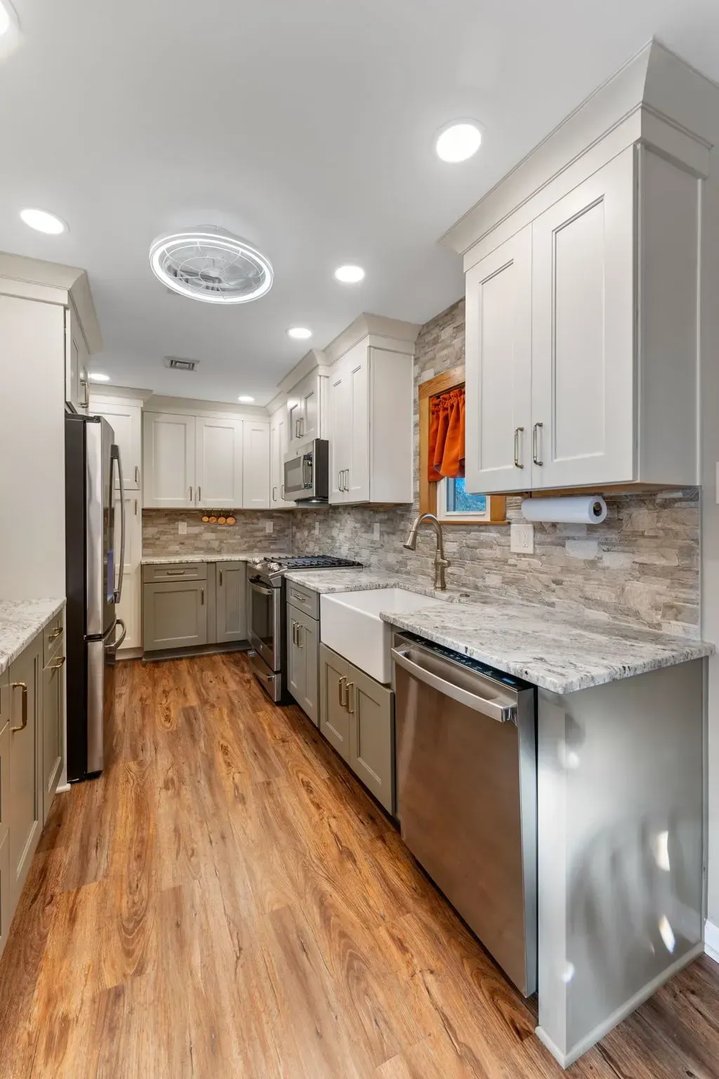 Bright modern galley kitchen with white cabinets, stainless appliances, granite counters, and wood floors In Bucks County PA