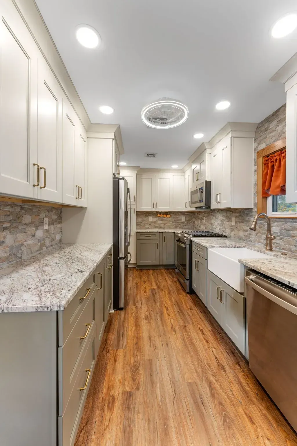 Bright modern galley kitchen with white cabinets, granite counters, wood floor, and stainless steel appliances In Bucks County PA