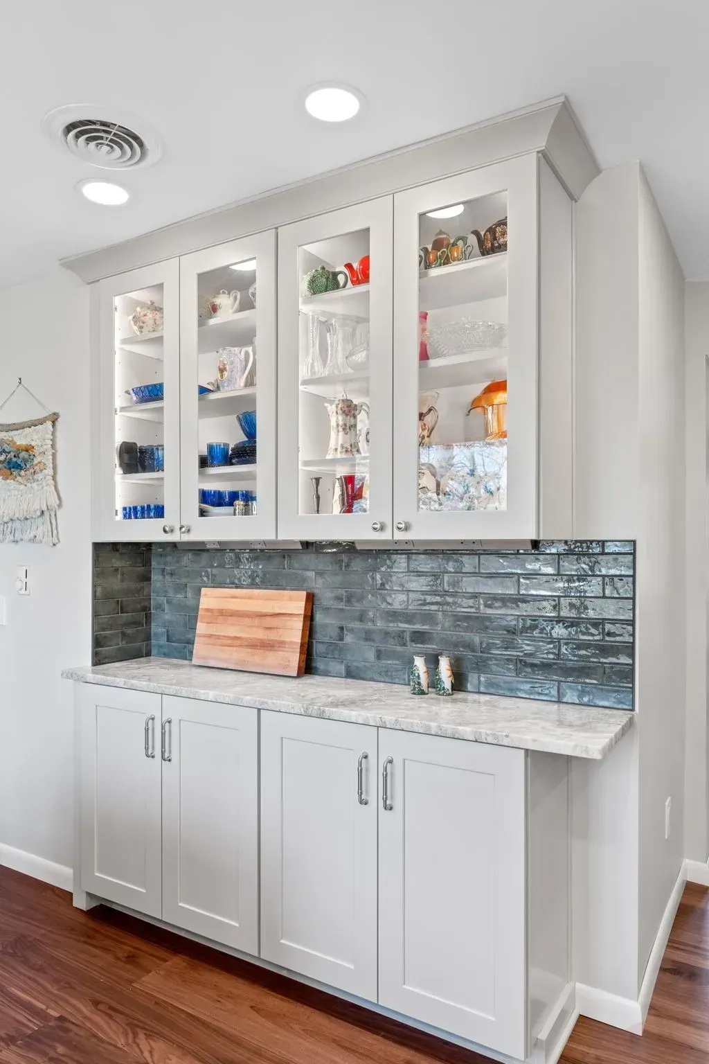 Built-in white cabinet with glass doors, countertop, and blue tile backsplash in a bright room In Bucks Country PA