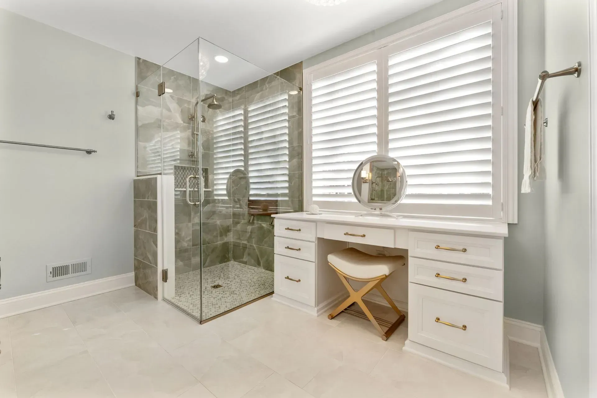 Bright modern bathroom with glass shower, white vanity, and large window blinds  In Bucks County PA