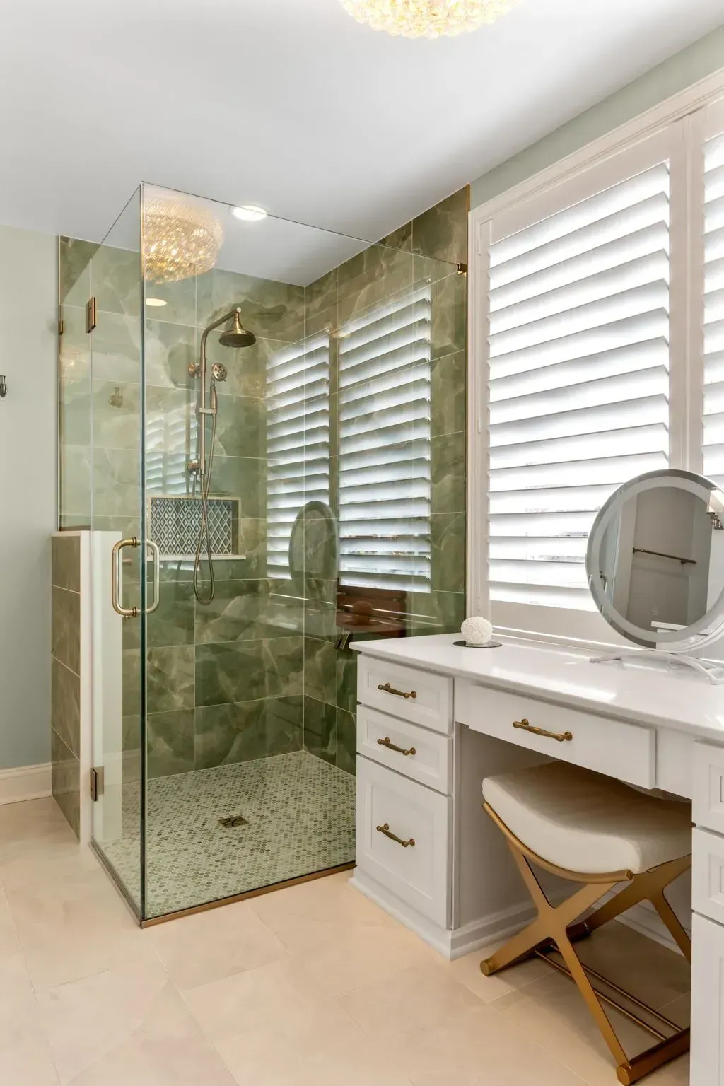Modern bathroom with glass shower, marble-look tile, white vanity, round mirror, and window blinds In Bucks County PA