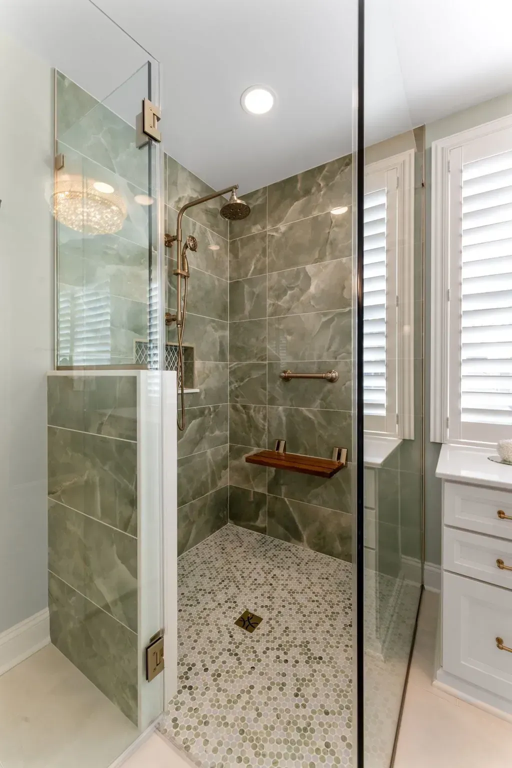 Modern glass walk-in shower with stone tile walls and pebble floor in a bright bathroom In Bucks County PA