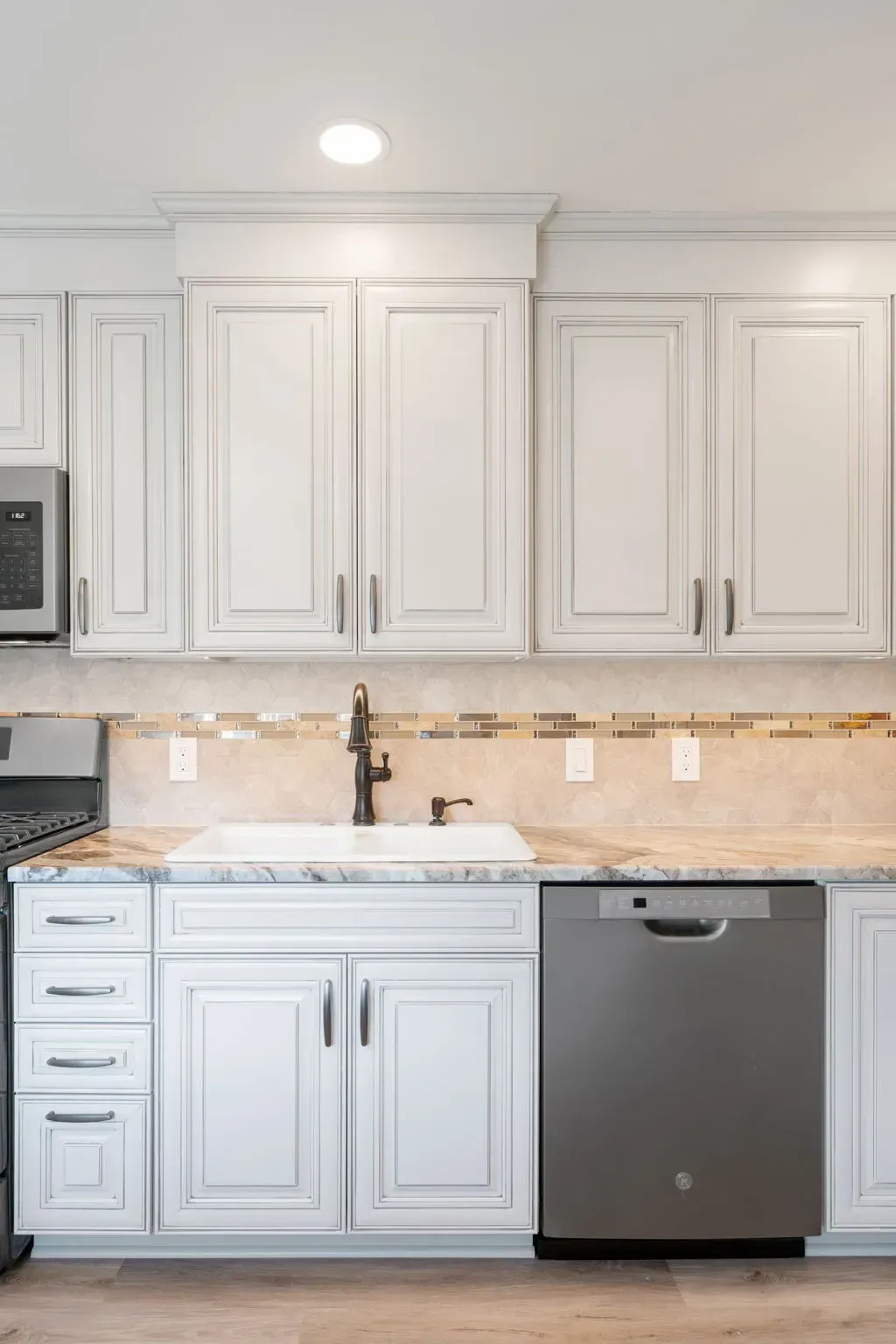 White kitchen with shaker cabinets, marble backsplash, and stainless steel dishwasher  In Bucks County PA