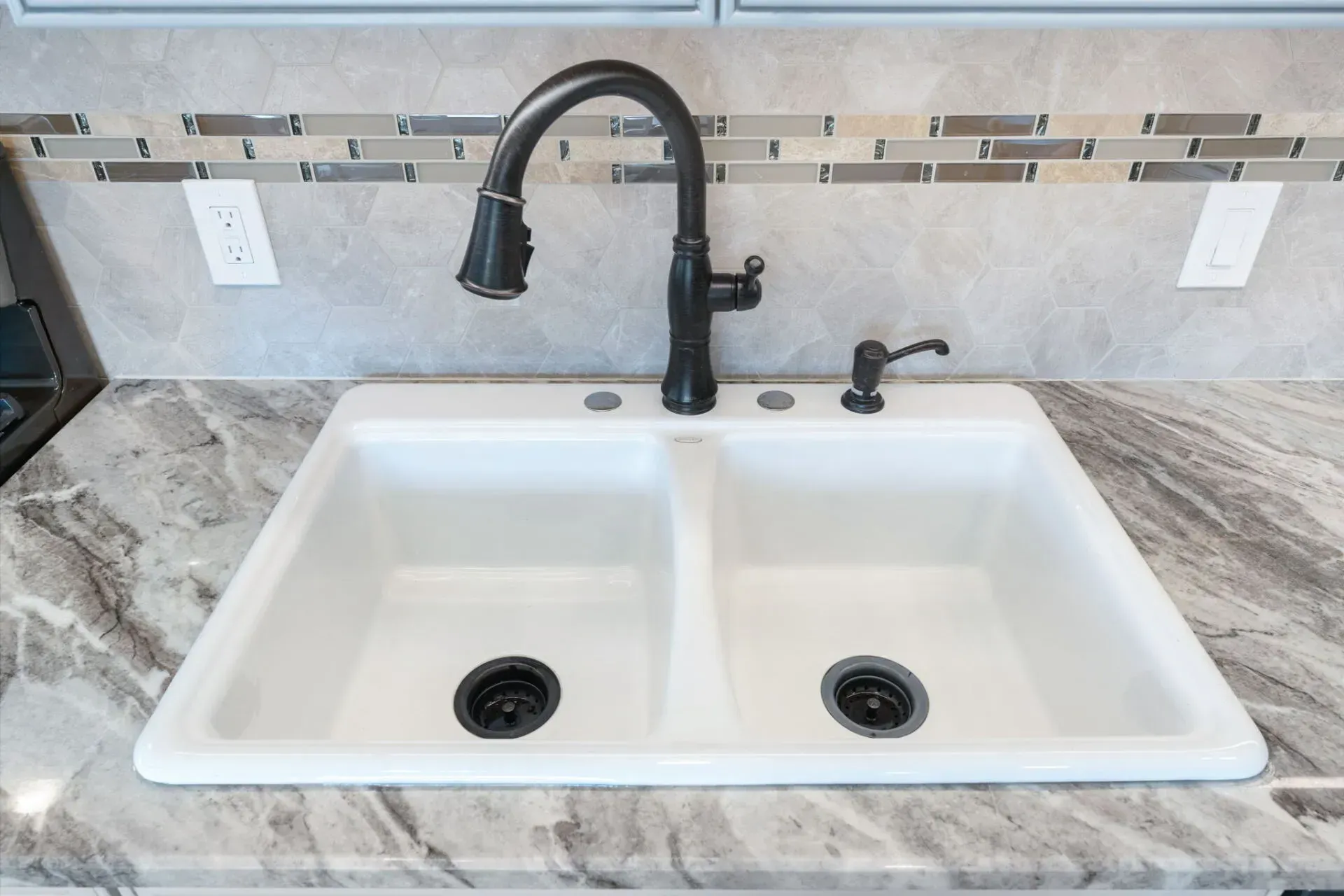 White double-basin kitchen sink with black faucet and marble countertop backsplash  In Bucks County PA