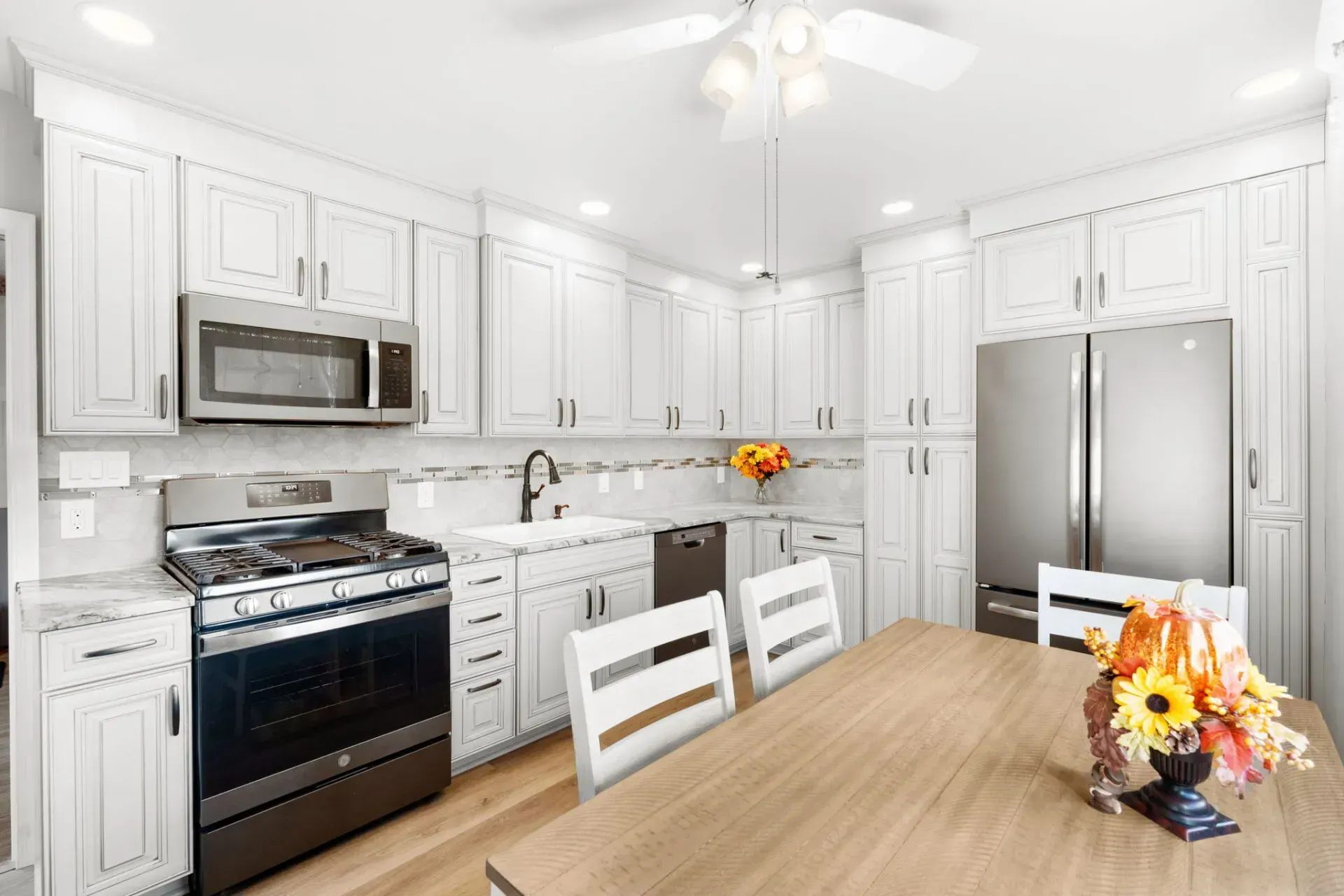 Bright white kitchen with stainless appliances, wood table, and autumn centerpiece  In Bucks County PA
