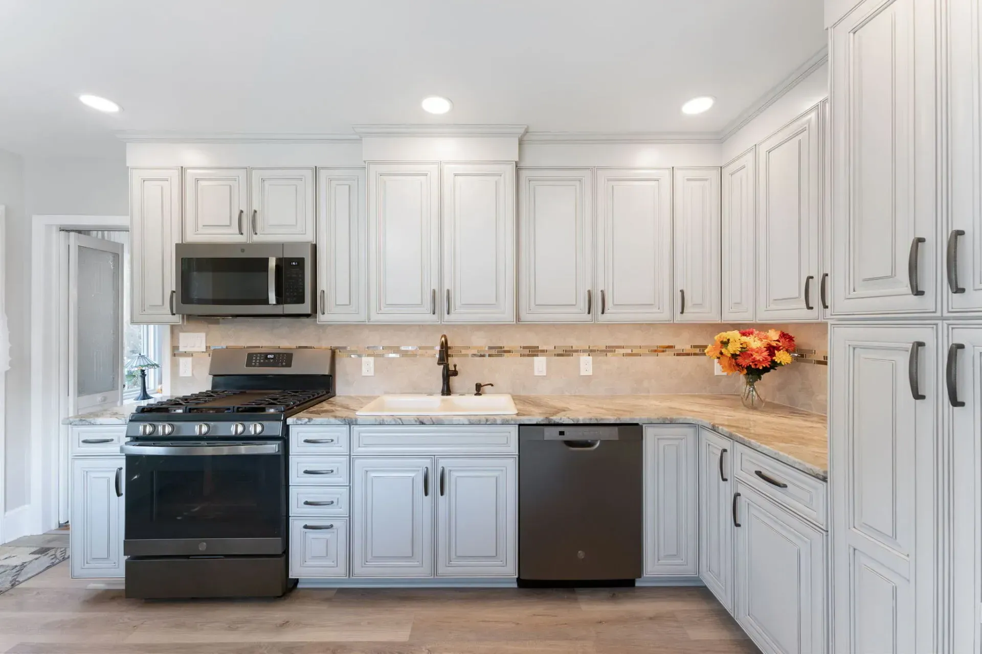 Bright modern kitchen with white cabinets, stainless appliances, and beige tile backsplash  In Bucks County PA