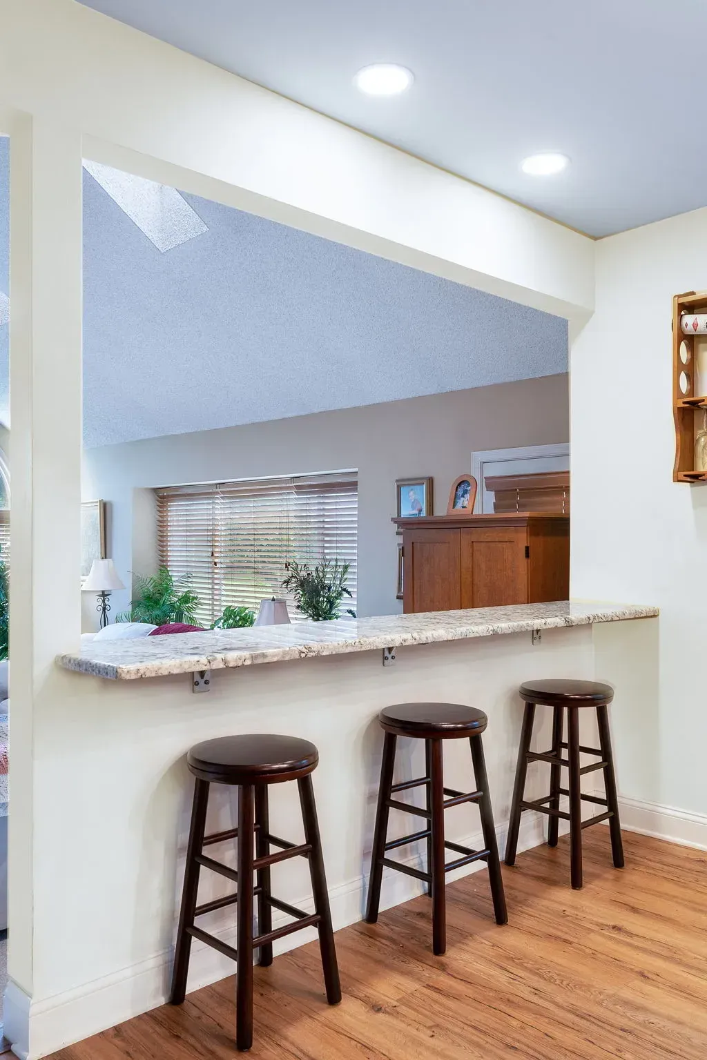 Kitchen pass-through with granite counter and three wooden bar stools beneath it In Bucks Country PA