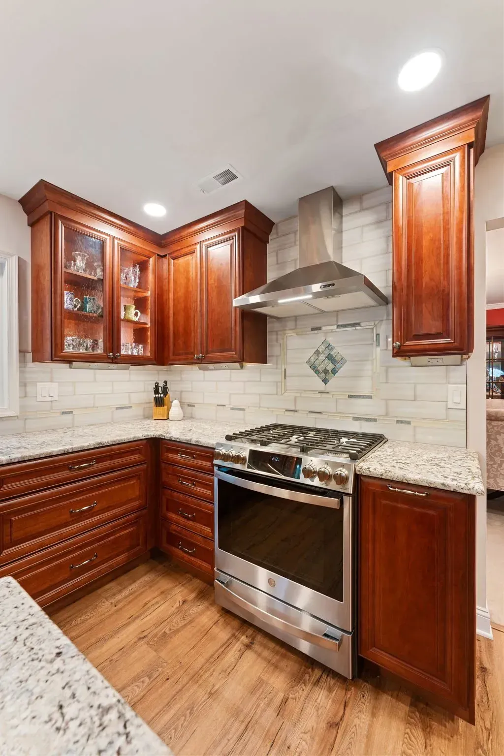 Modern kitchen with cherry cabinets, stainless steel range hood, and white tile backsplash In Bucks Country PA