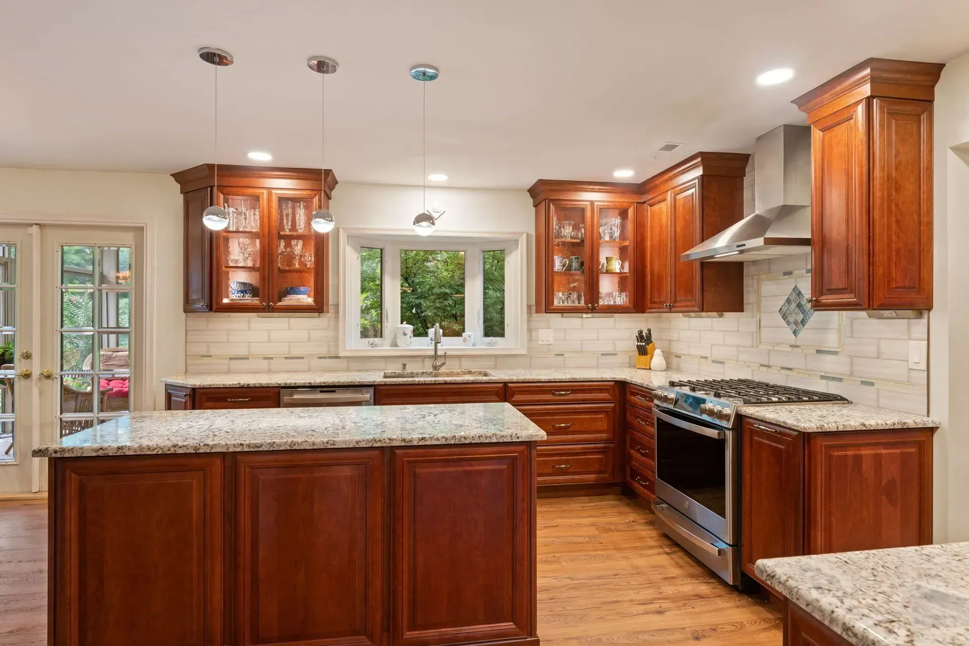 Modern kitchen with cherry cabinets, granite counters, stainless steel range, and a window above the sink In Bucks Country PA