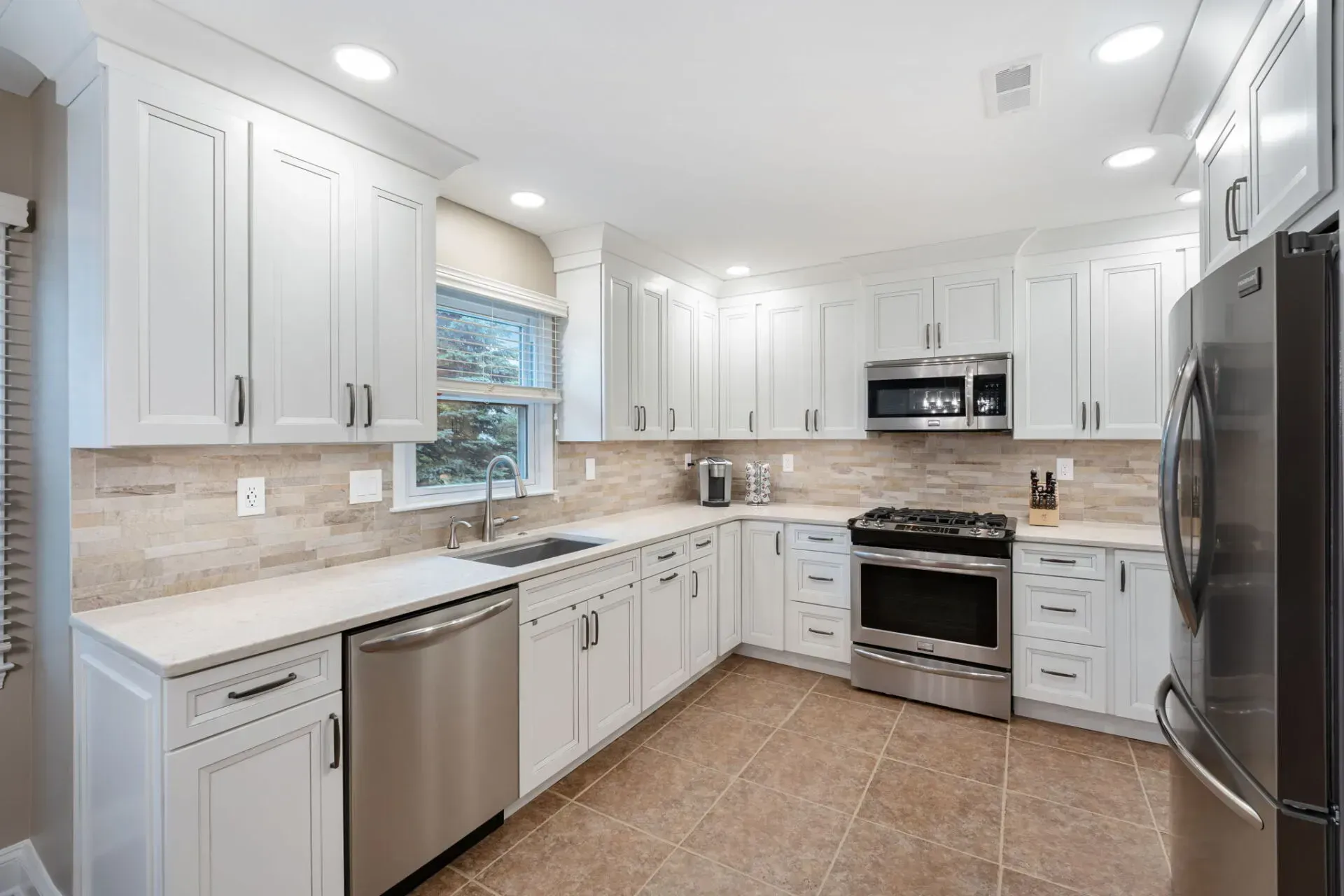 Bright white modern kitchen with stainless steel appliances and tan tile floor  In Bucks County PA
