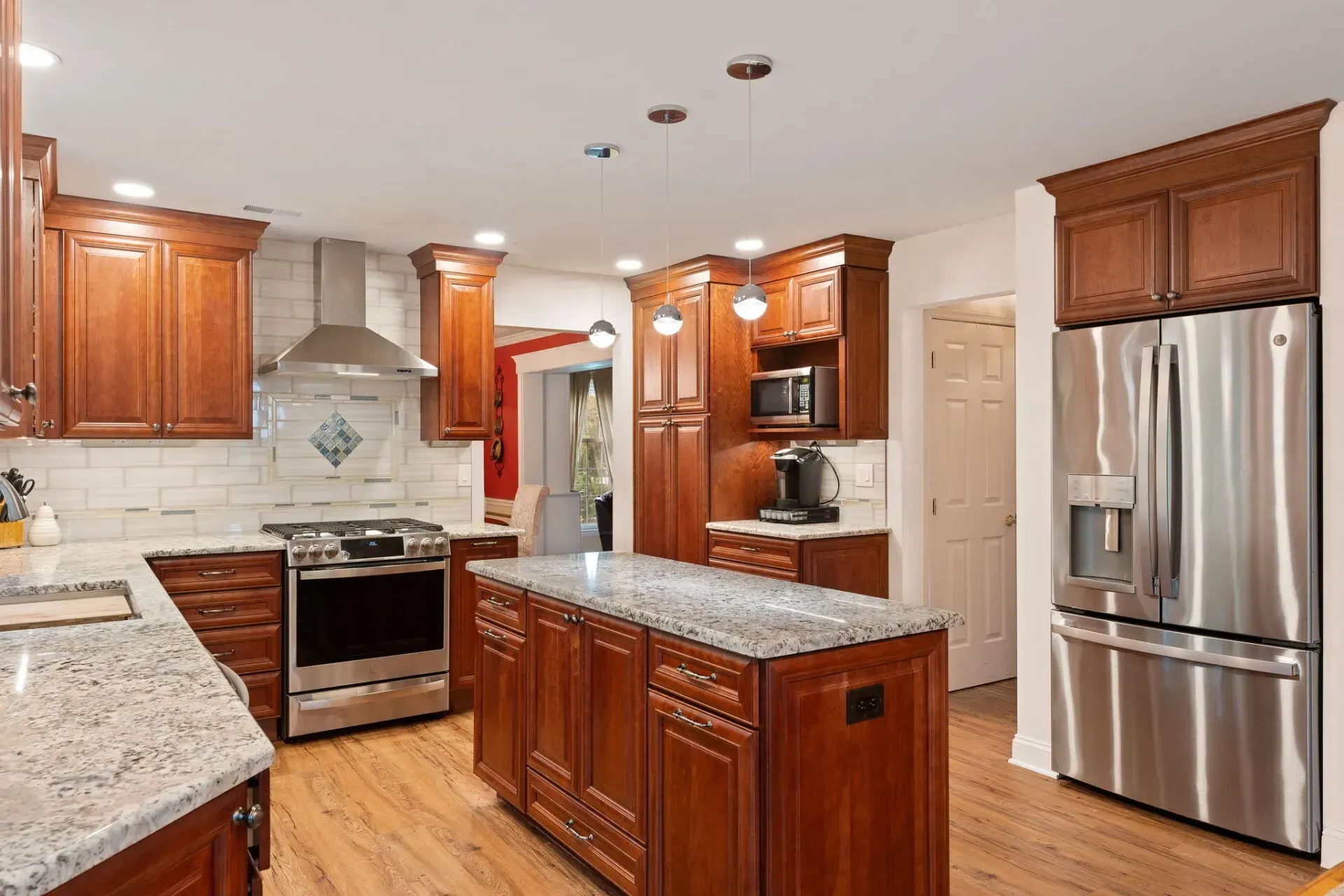 Modern kitchen with cherry cabinets, granite island, stainless steel appliances, and hardwood floors In Bucks Country PA