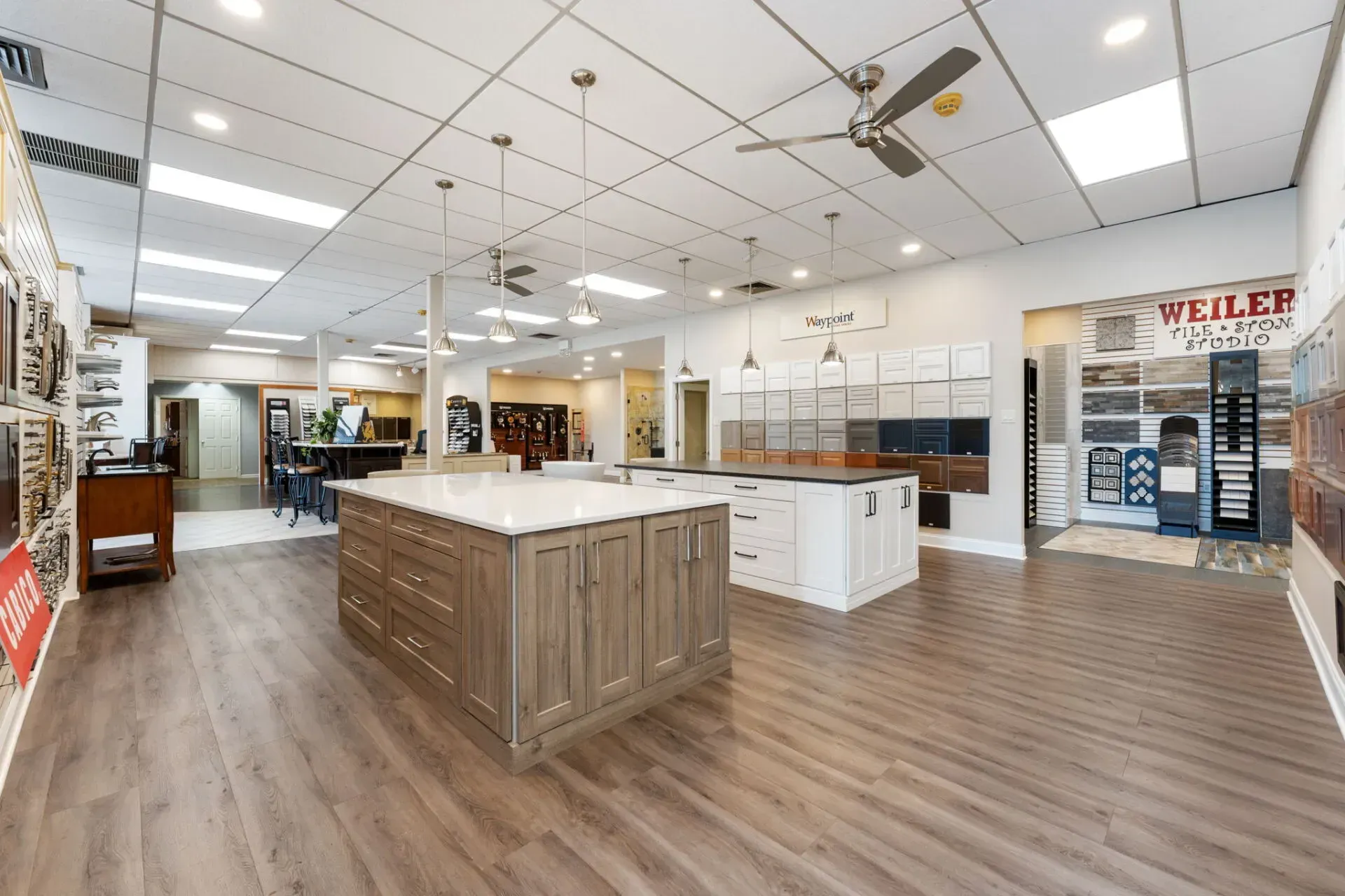 Empty retail showroom with wood flooring, central island displays, and ceiling fans under bright lights In Bucks Country PA