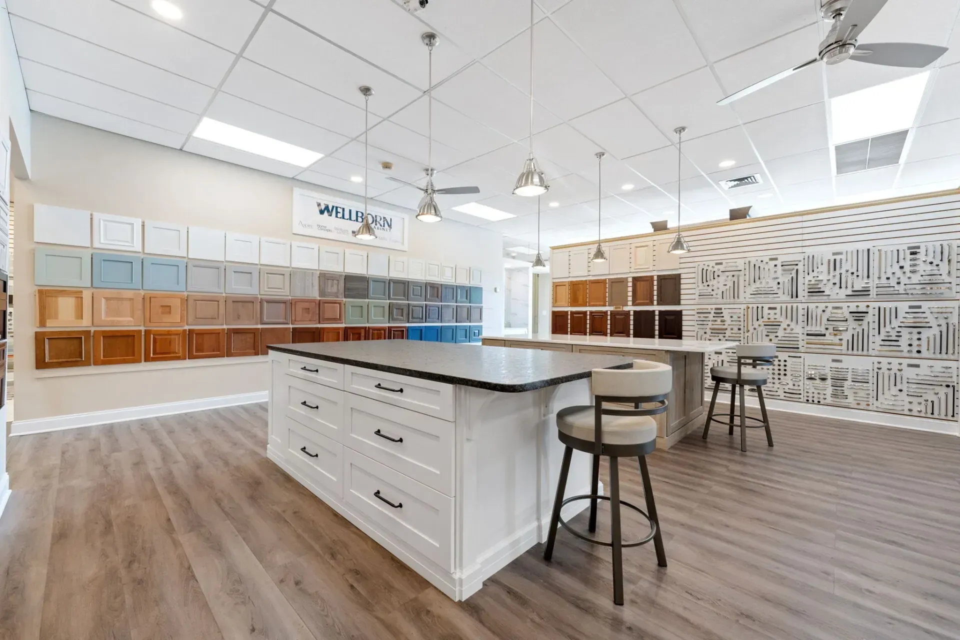 Bright modern kitchen showroom with white cabinets, island seating, and wood flooring In Bucks Country PA