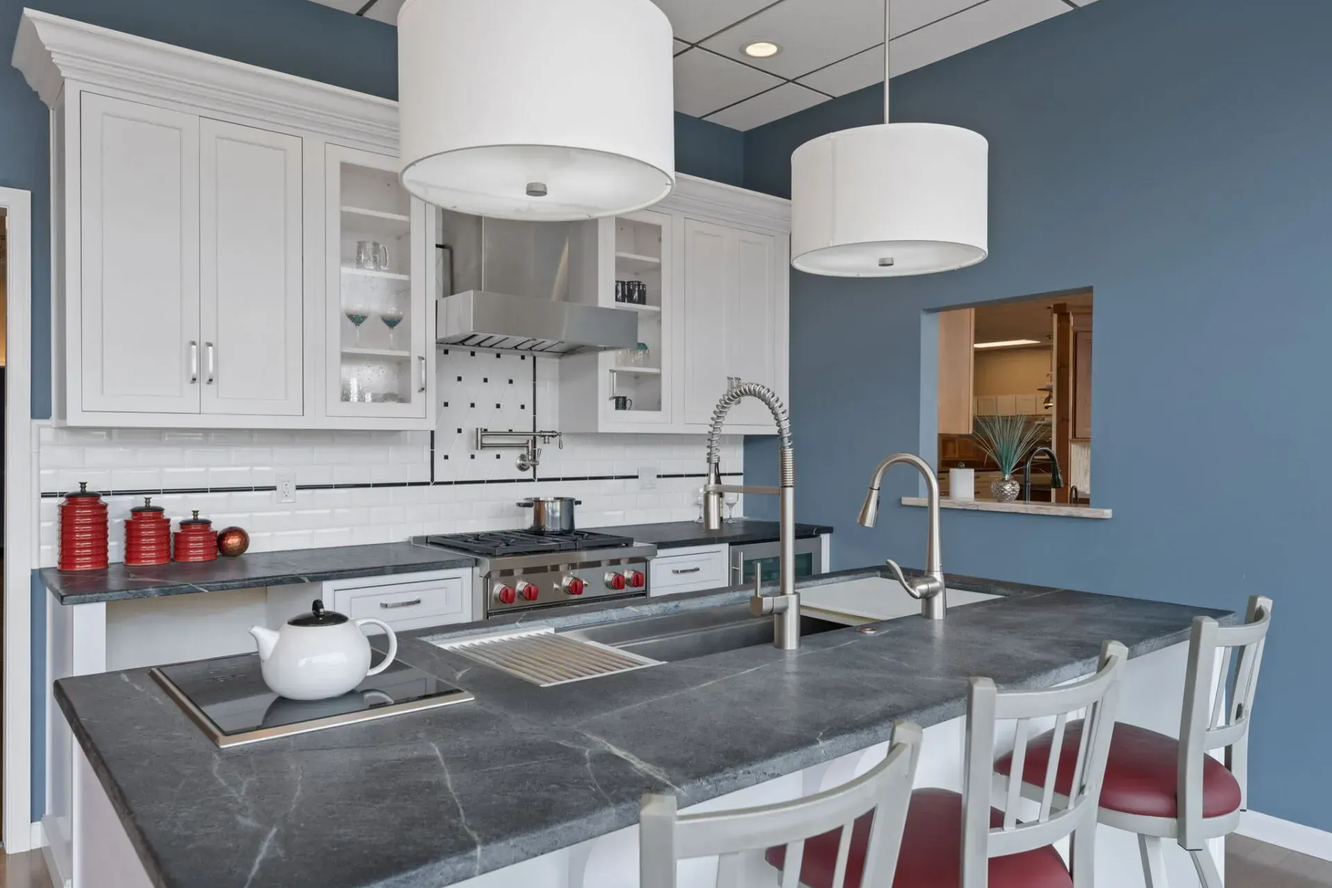 Modern kitchen with blue walls, white cabinets, gray island, and pendant lights  In Bucks County PA