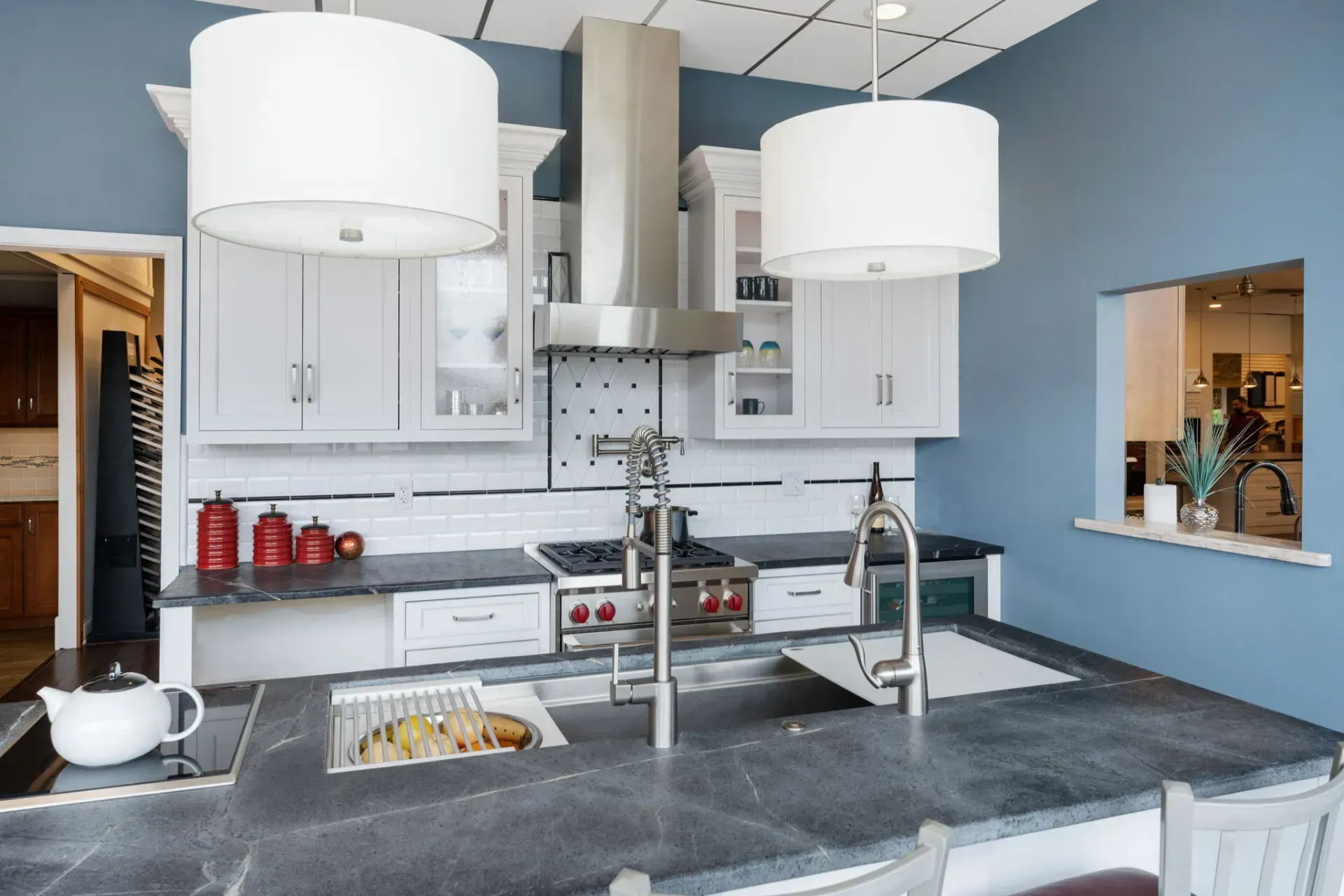 Modern kitchen with gray island, white cabinets, stainless range hood, and large pendant lights  In Bucks County PA