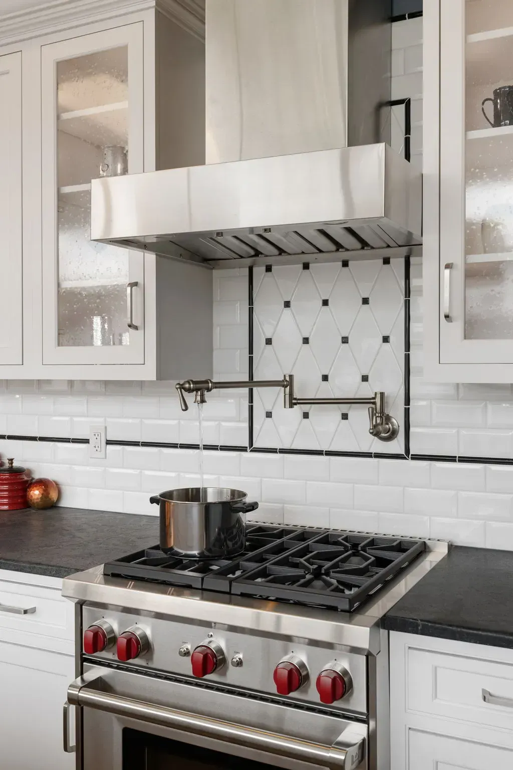 Modern kitchen with stainless steel gas range, white cabinets, and a pot on the stove beneath a vent hood  In Bucks County PA