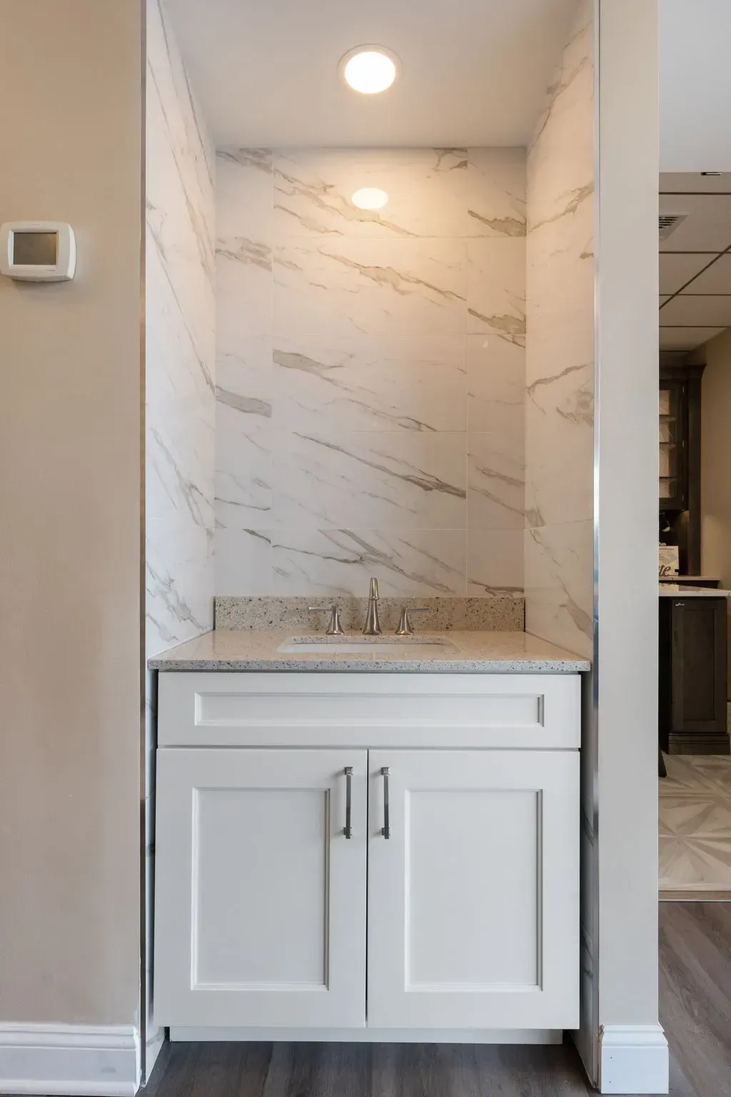 Built-in white marble-look shower niche above a white vanity cabinet in a hallway nook  In Bucks County PA