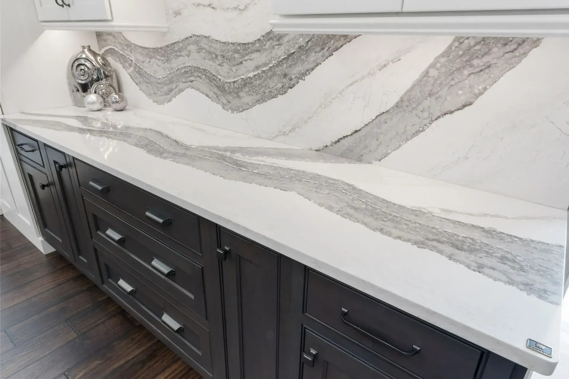 Modern kitchen vanity with dark cabinets and a white-and-gray marble countertop and backsplash  In Bucks County PA