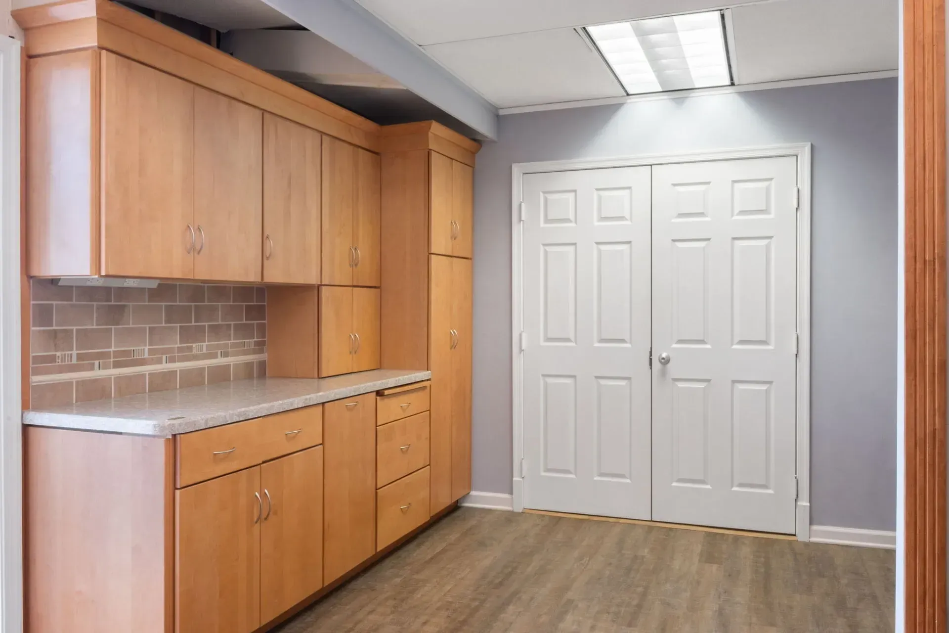 Empty room with wooden cabinets, gray walls, and white double closet doors  In Bucks County PA