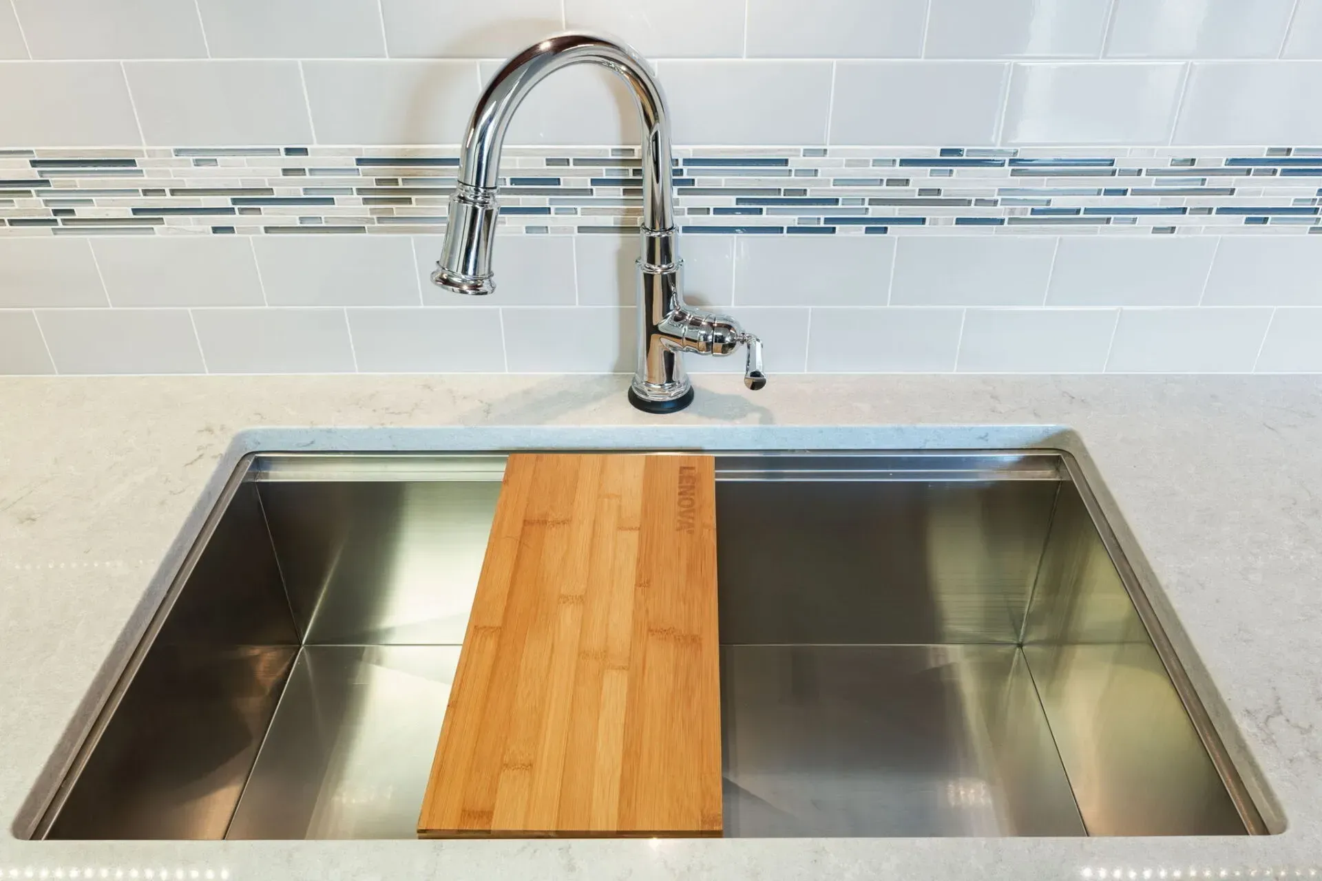 Stainless steel kitchen sink with a chrome faucet and a wooden cutting board insert  In Bucks County PA