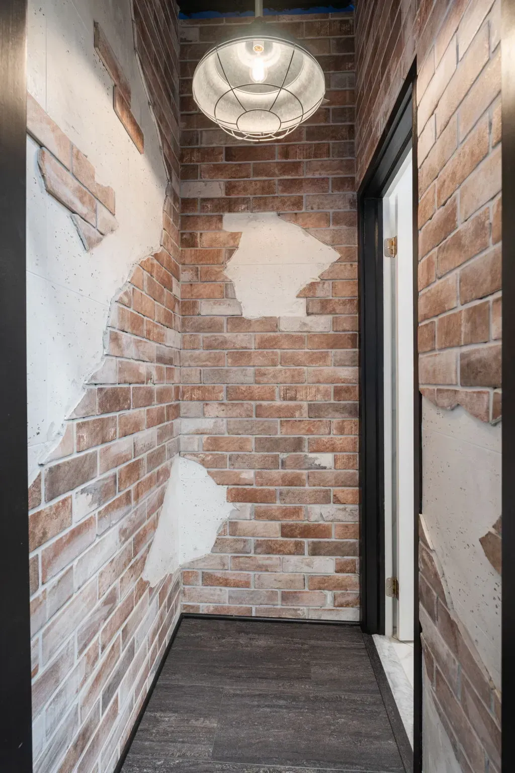 Narrow brick hallway with white-painted patches, dark carpet, and a round ceiling light  In Bucks County PA
