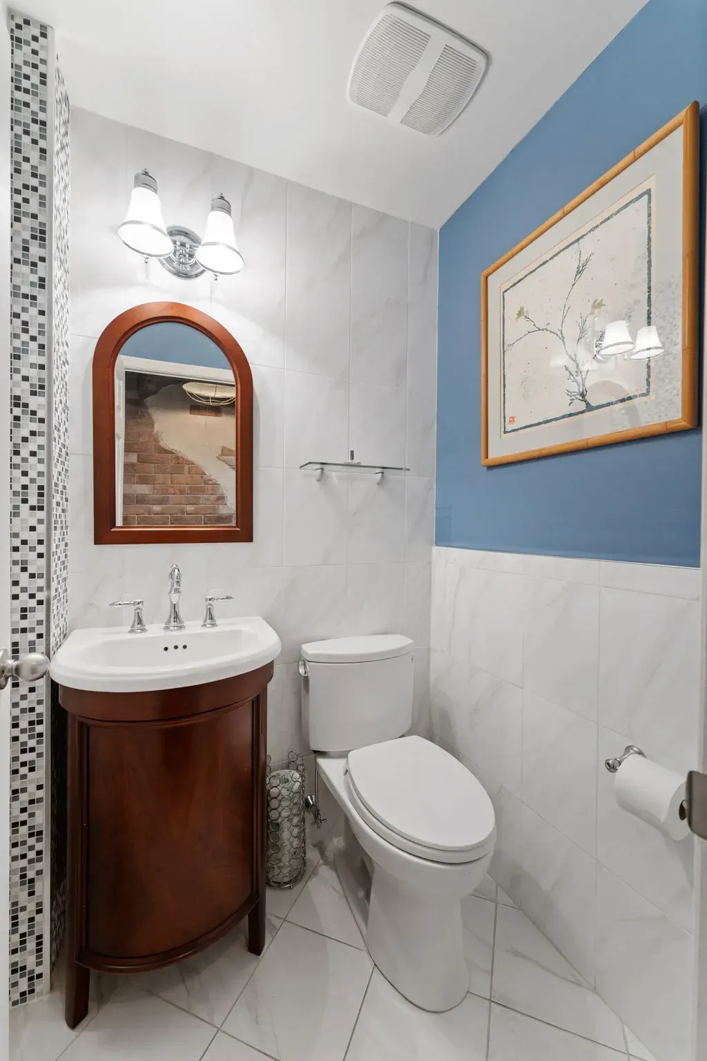 Small bathroom with pedestal sink, toilet, wall mirror, and blue accent wall  In Bucks County PA