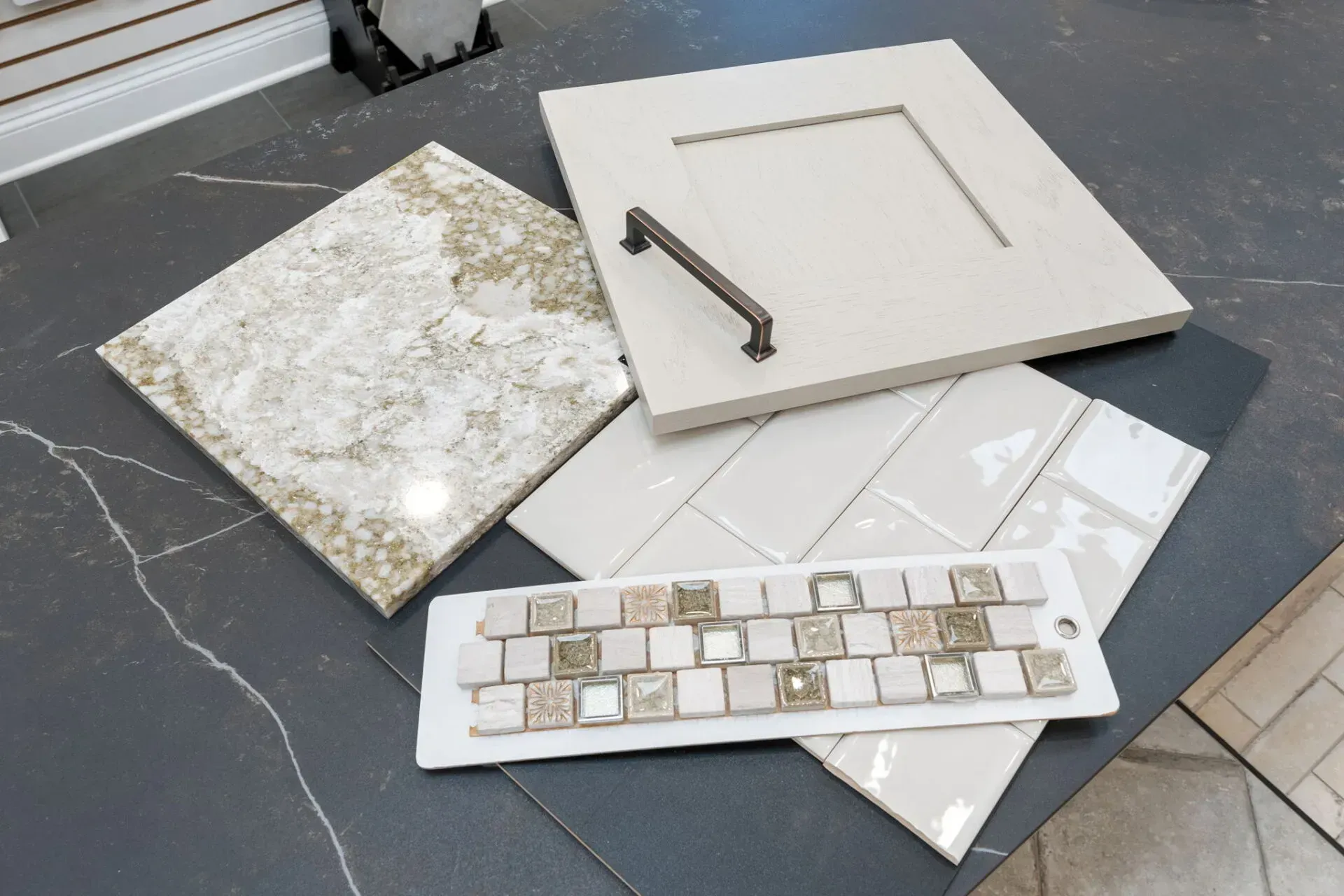 Assorted square tiles and tile samples arranged on a floor, including a decorative mosaic and sample board  In Bucks County PA