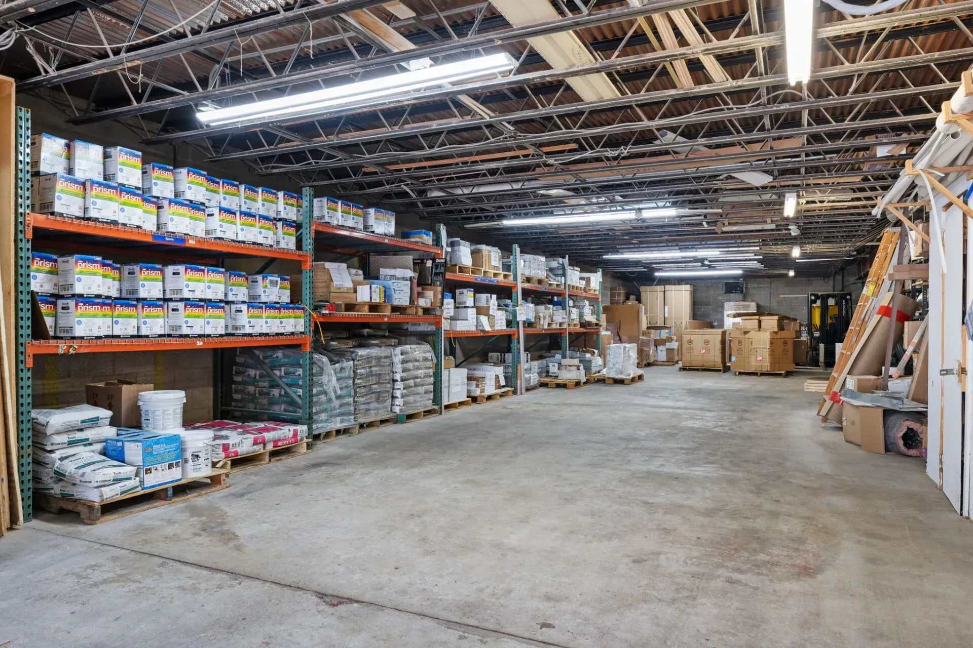 Warehouse aisle with stacked boxes, pallets, and shelves under exposed ceiling beams  In Bucks County PA