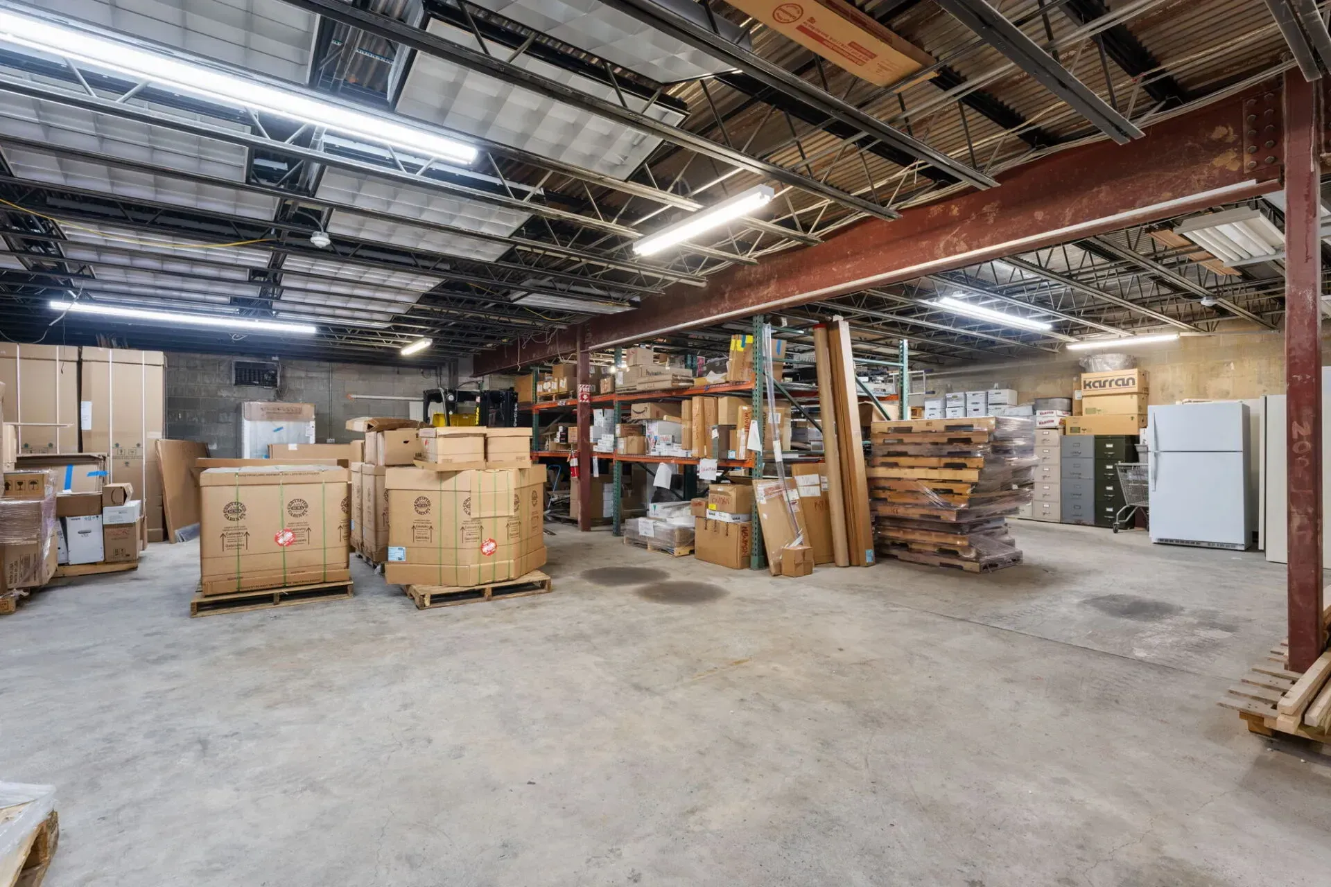 Industrial warehouse interior with stacked boxes, pallets, shelves, and exposed ceiling beams  In Bucks County PA