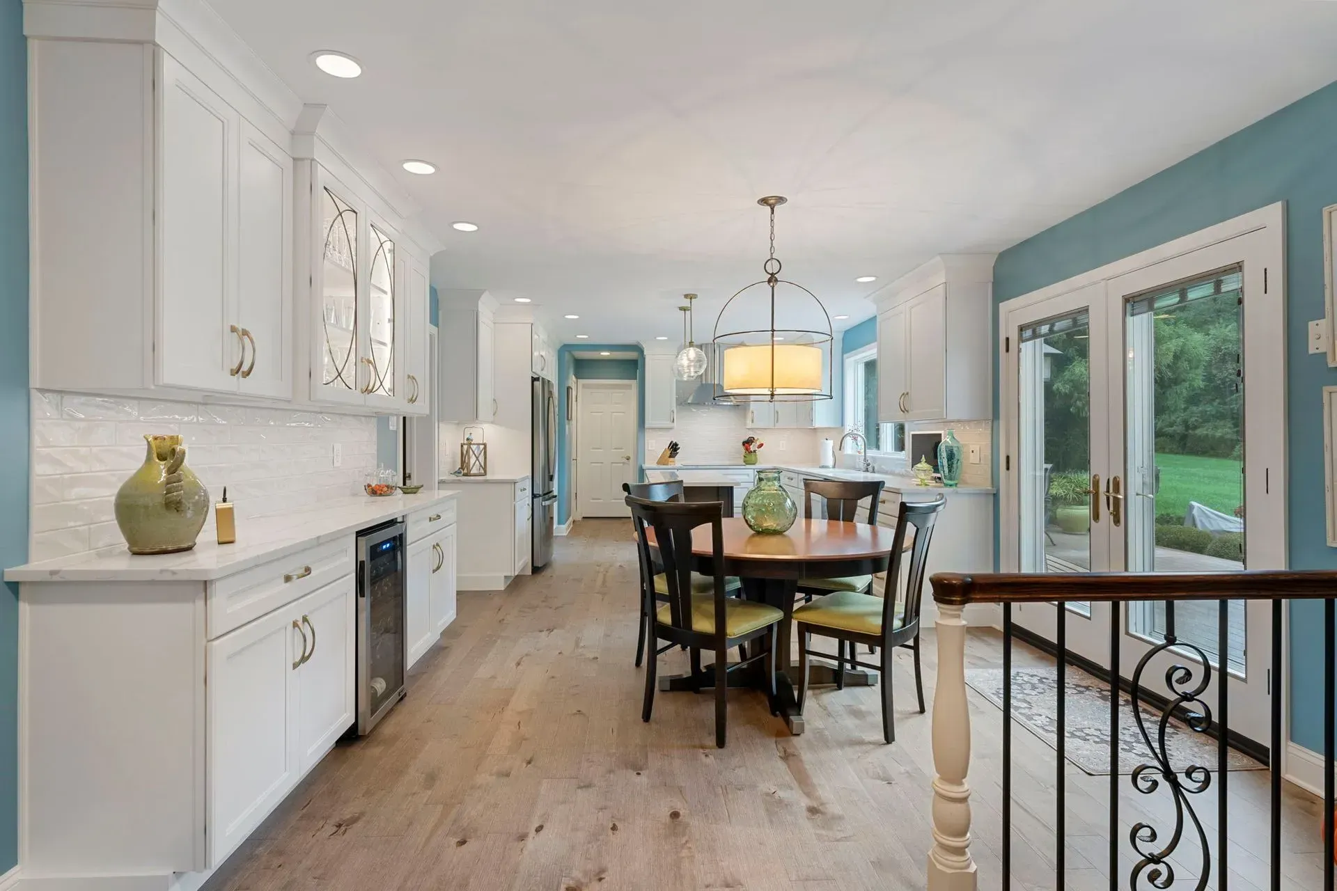 Bright white kitchen and dining area with blue walls, wood floors, and large glass doors to patio  In Bucks County PA