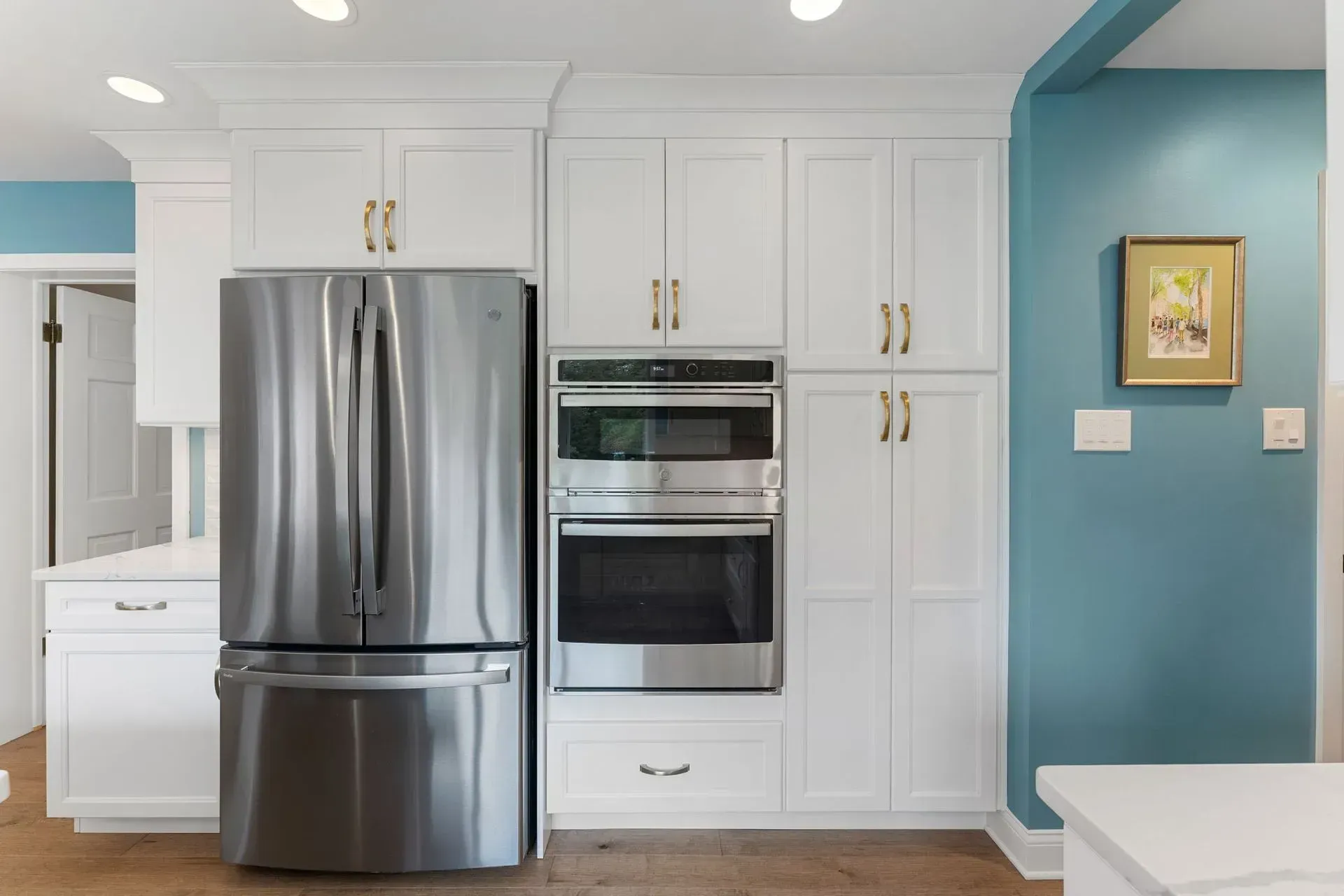 Bright kitchen with stainless steel fridge and oven, white cabinets, and teal accent wall  In Bucks County PA