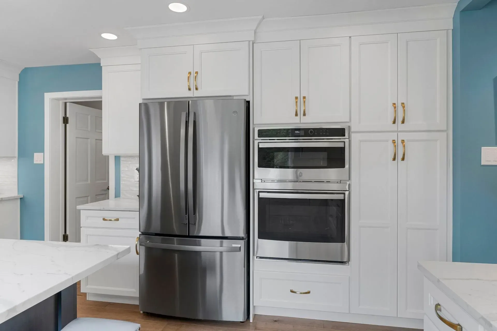 Bright white kitchen with stainless steel refrigerator, double oven, and light blue walls   In Bucks County PA