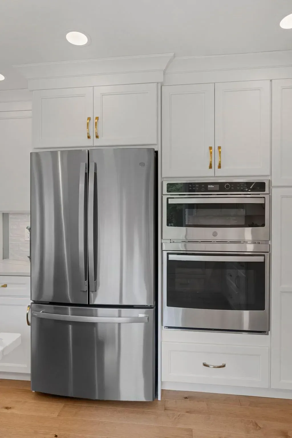 Modern kitchen with stainless steel refrigerator and built-in double oven in white cabinetry  In Bucks County PA