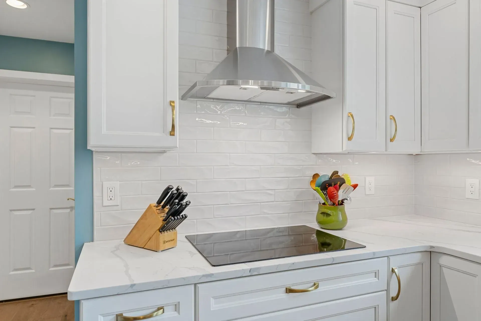 White kitchen with stainless range hood, stovetop, knife block, and fruit bowl on the counter  In Bucks County PA