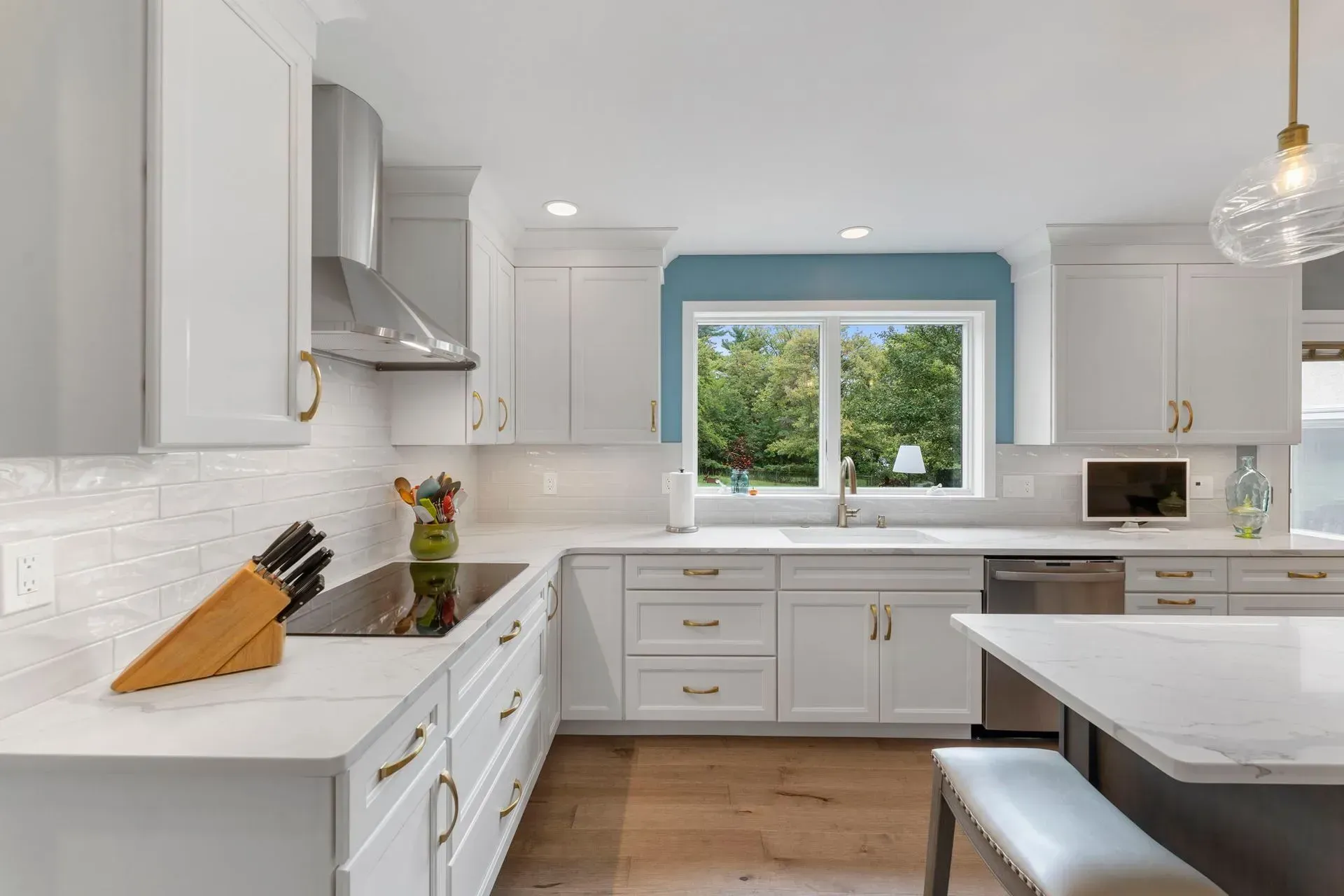 Bright modern kitchen with white cabinets, marble island, and window over the sink  In Bucks County PA