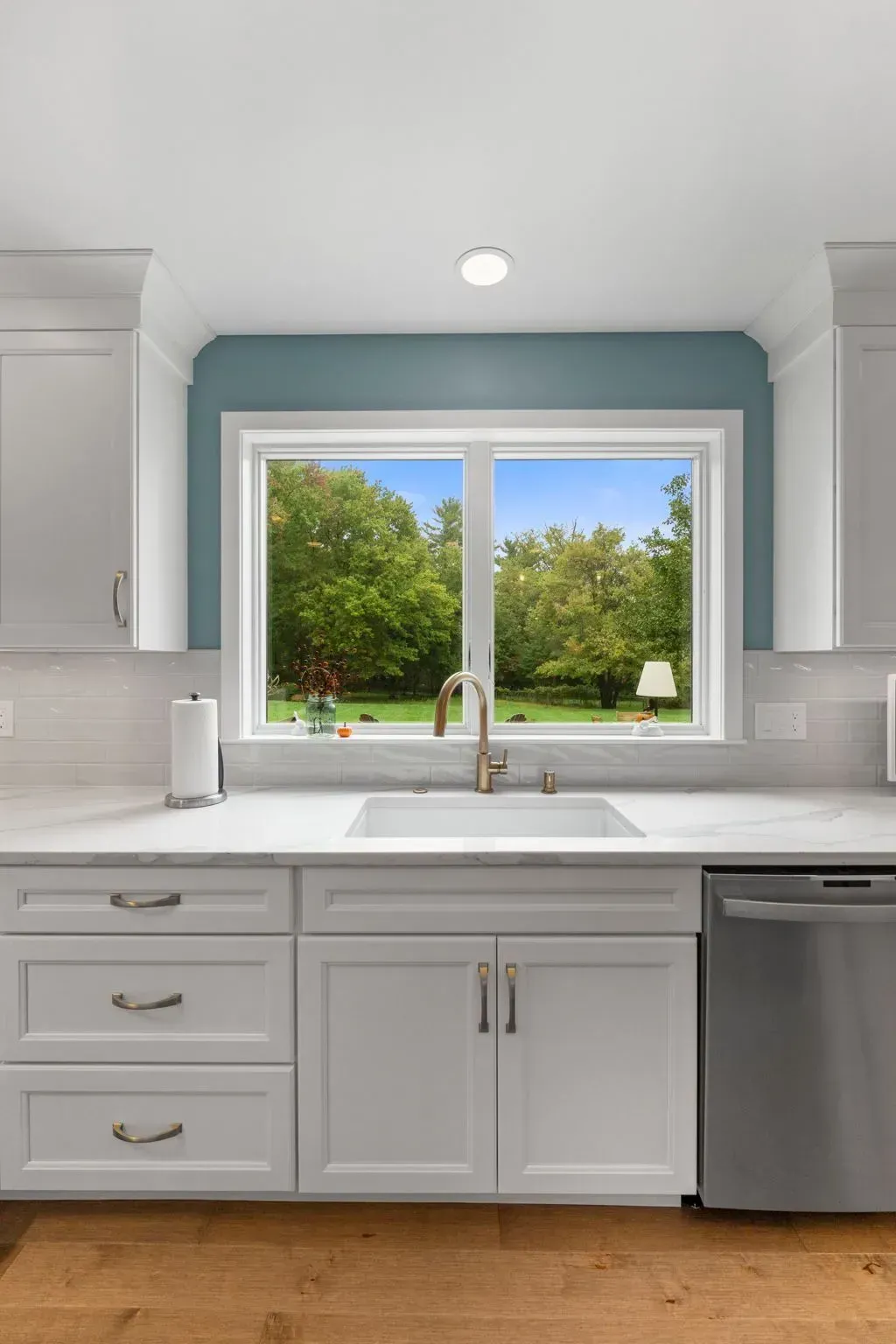 Bright kitchen with white cabinets, a large window, and a stainless dishwasher below the sink  In Bucks County PA