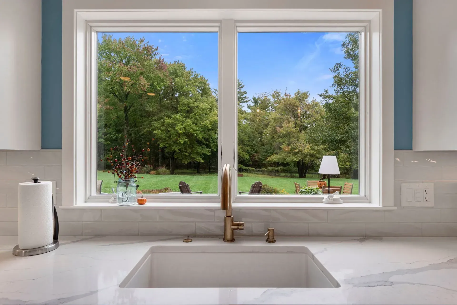Bright kitchen sink beneath a window overlooking a green backyard and blue sky  In Bucks County PA