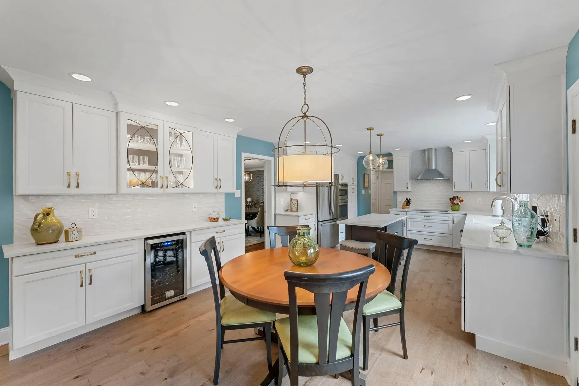 Bright kitchen with white cabinets, blue walls, round wooden table, and hanging pendant light  In Bucks County PA