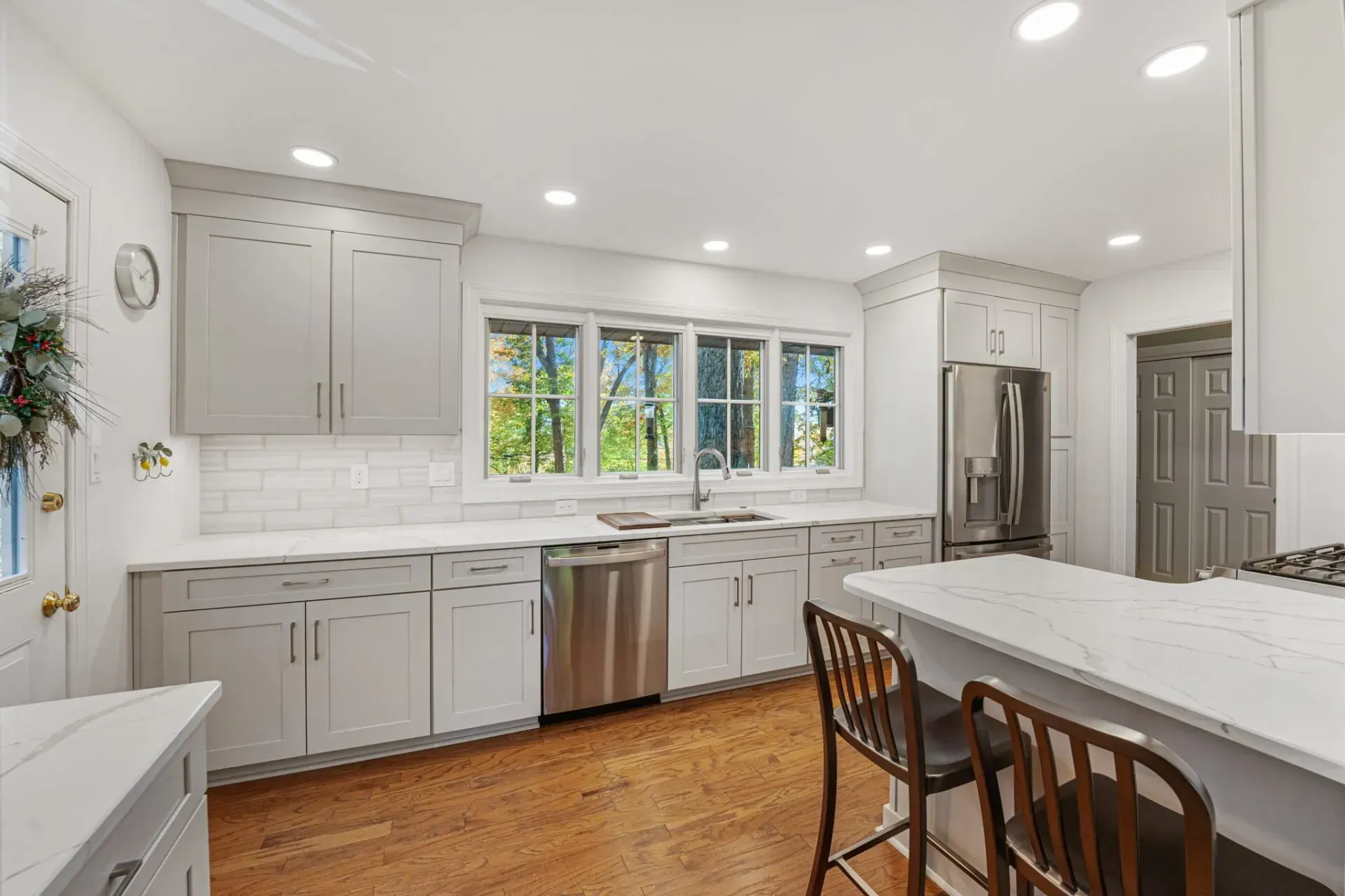 Bright modern kitchen with gray cabinets, white countertops, stainless appliances, and large window in Bucks County PA